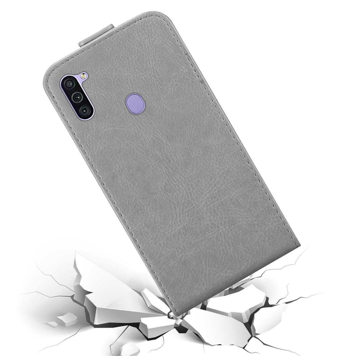 Graue Handyhülle auf weißem Untergrund, teilweise zerbrochen. Telefon ist angewinkelt mit Kamera.