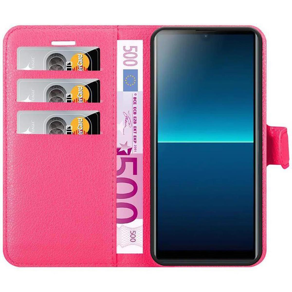 Custodia per telefono rosa con tre slot per carte, una banconota da 500 euro e un telefono. Lo schermo del telefono è blu.