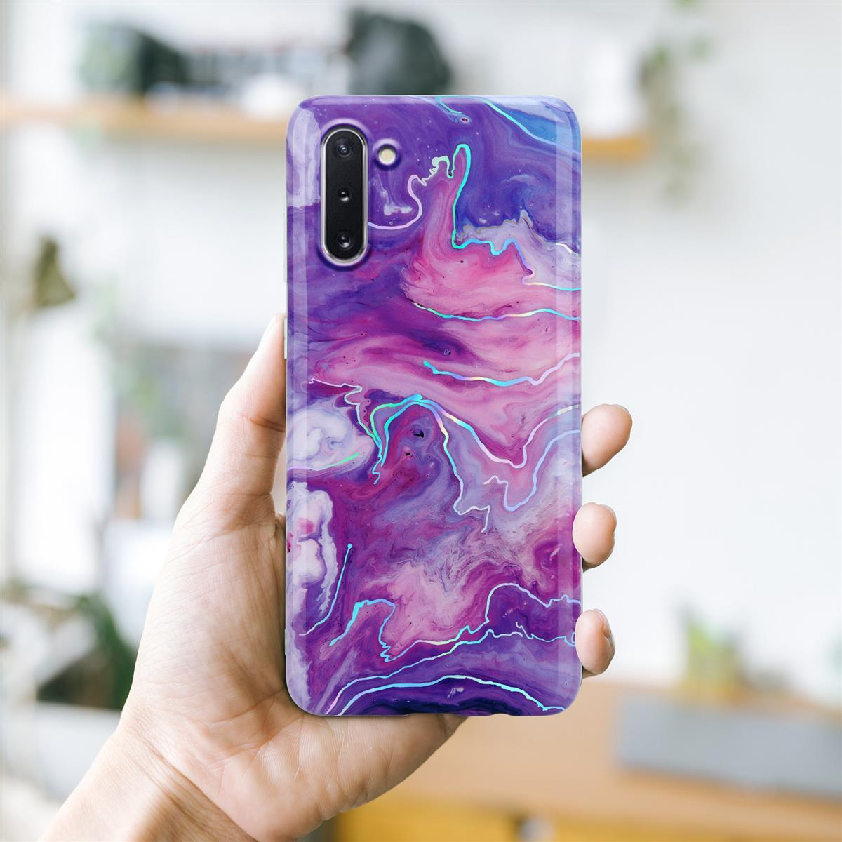 Mano che tiene una custodia per telefono con un design astratto colorato. La custodia è viola, rosa e blu.