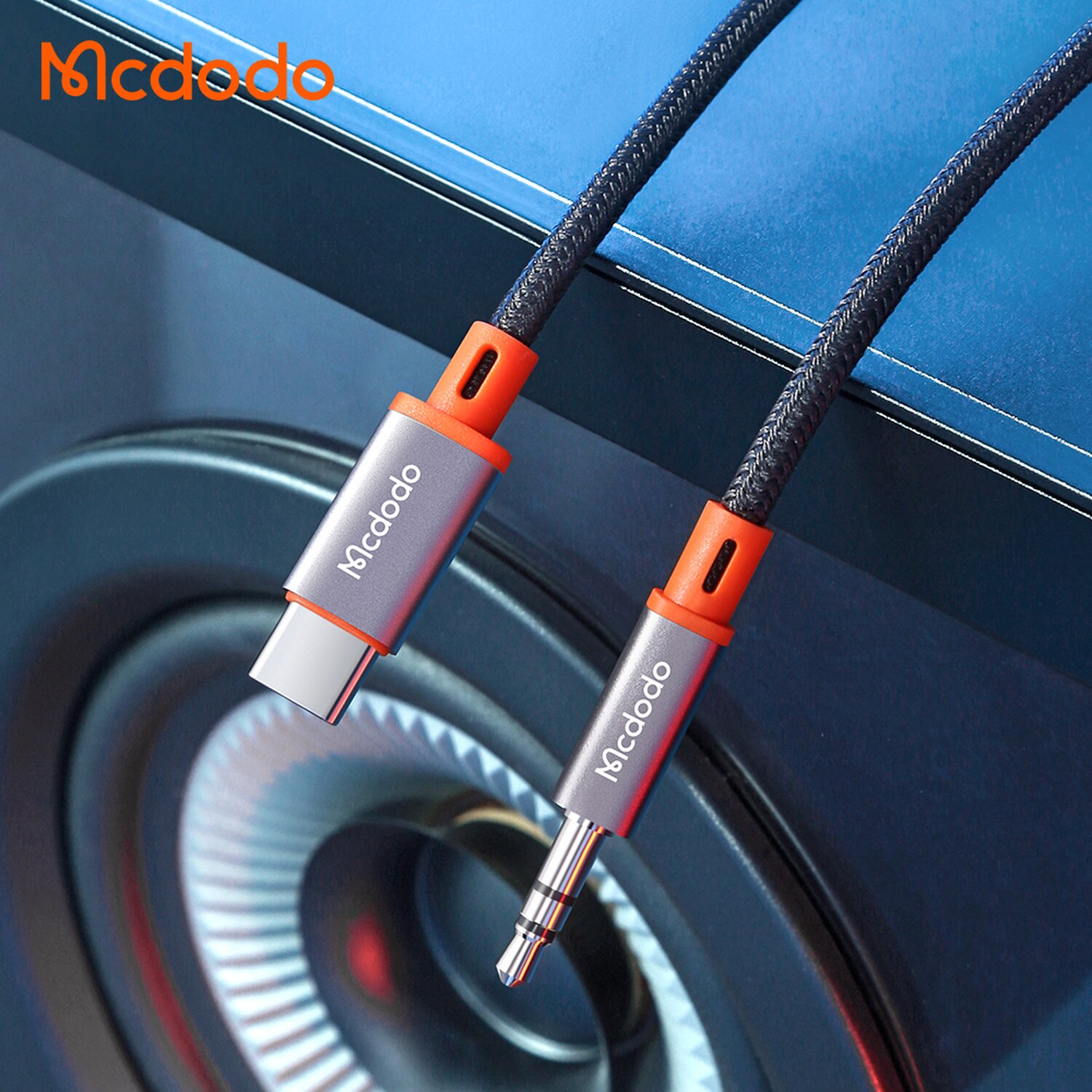 Un cavo audio da USB-C a 3,5 mm argentato e arancione. Il cavo è nero e intrecciato.