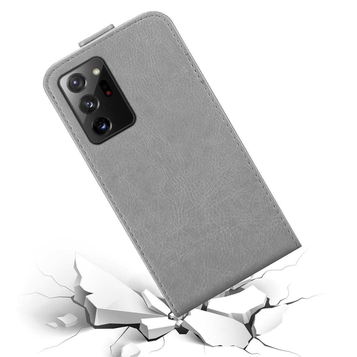 Una custodia grigia per telefono con un telefono nero all'interno. Il telefono sta rompendo una superficie bianca. La custodia ha delle fotocamere.