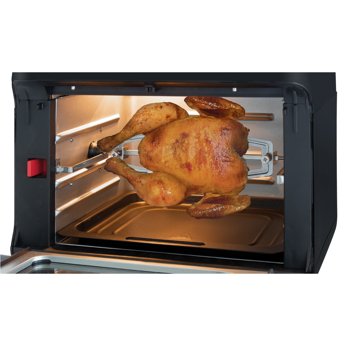 Pieczony kurczak na rożnie w czarnym piekarniku, z widocznymi nogami i skrzydłami oraz blachą do pieczenia poniżej.