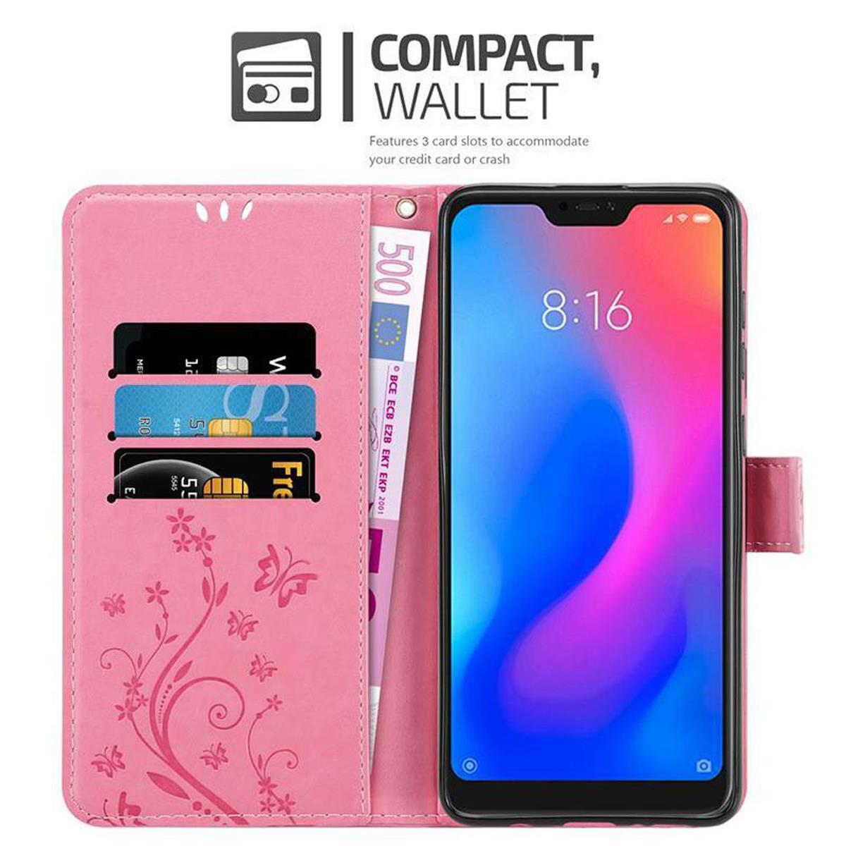 Portafoglio rosa con carte e denaro all'interno, e uno smartphone, su sfondo bianco.