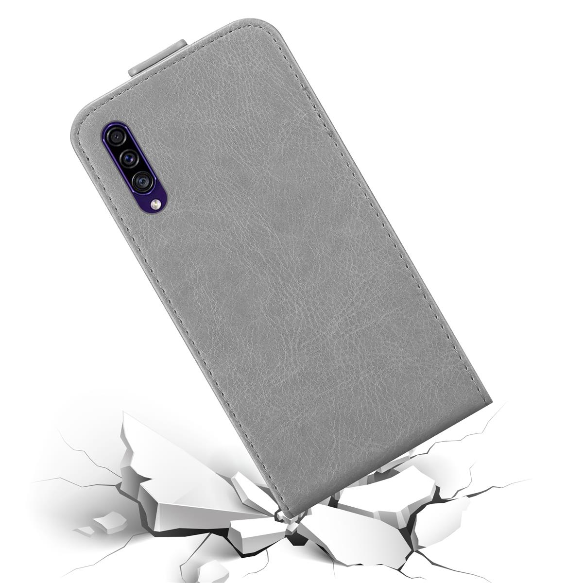 Custodia grigia per telefono su superficie bianca con crepe. La custodia ha una tripla fotocamera.
