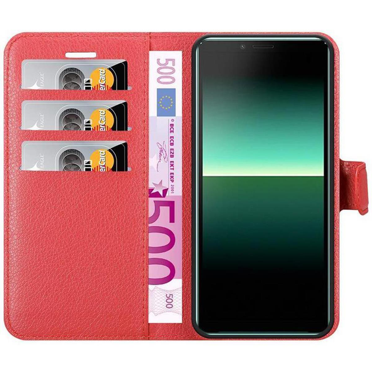 Custodia rossa, aperta, con tre fessure per carte e scomparto per soldi. Il telefono è nero.