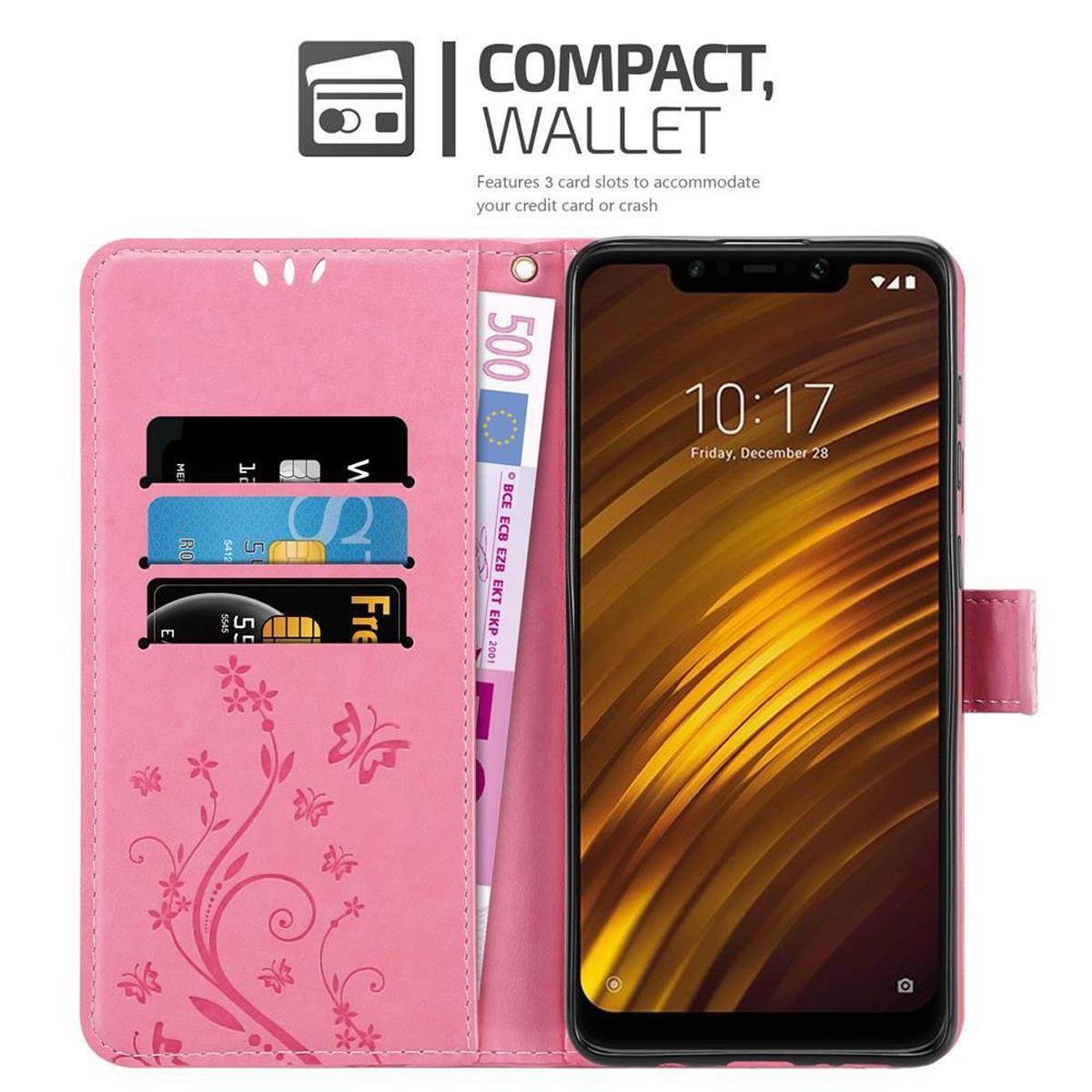 Custodia a portafoglio per telefono rosa aperta, che mostra carte e denaro. Schermo del telefono con l'ora. Testo in alto.