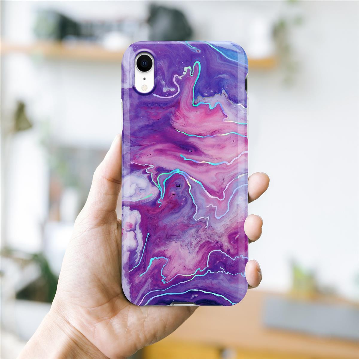 Mano che tiene una custodia per telefono marmorizzata viola, rosa e blu.