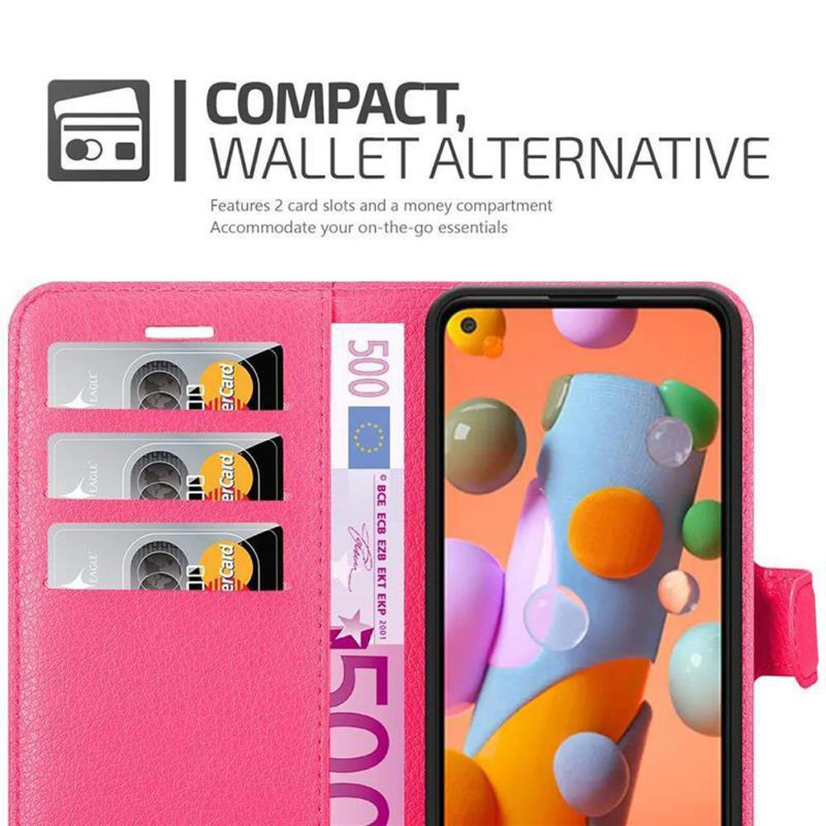Custodia a portafoglio rosa per telefono aperta con carte e denaro visibili. Lo schermo del telefono mostra forme colorate.