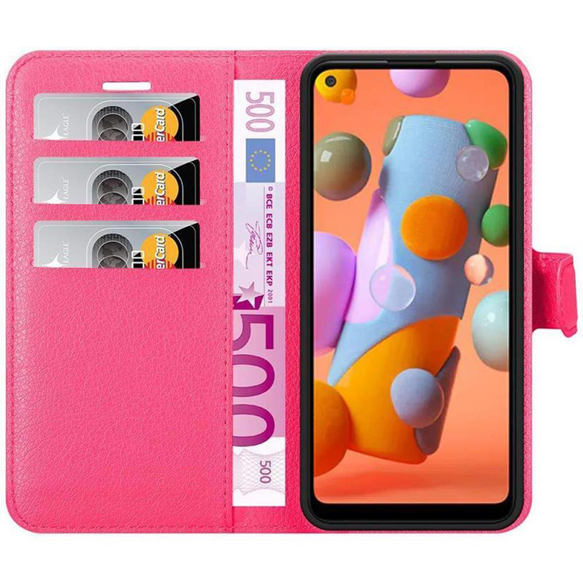 Custodia per telefono rosa, aperta, che mostra un telefono con schermo colorato, tre carte e una banconota da 500 euro.