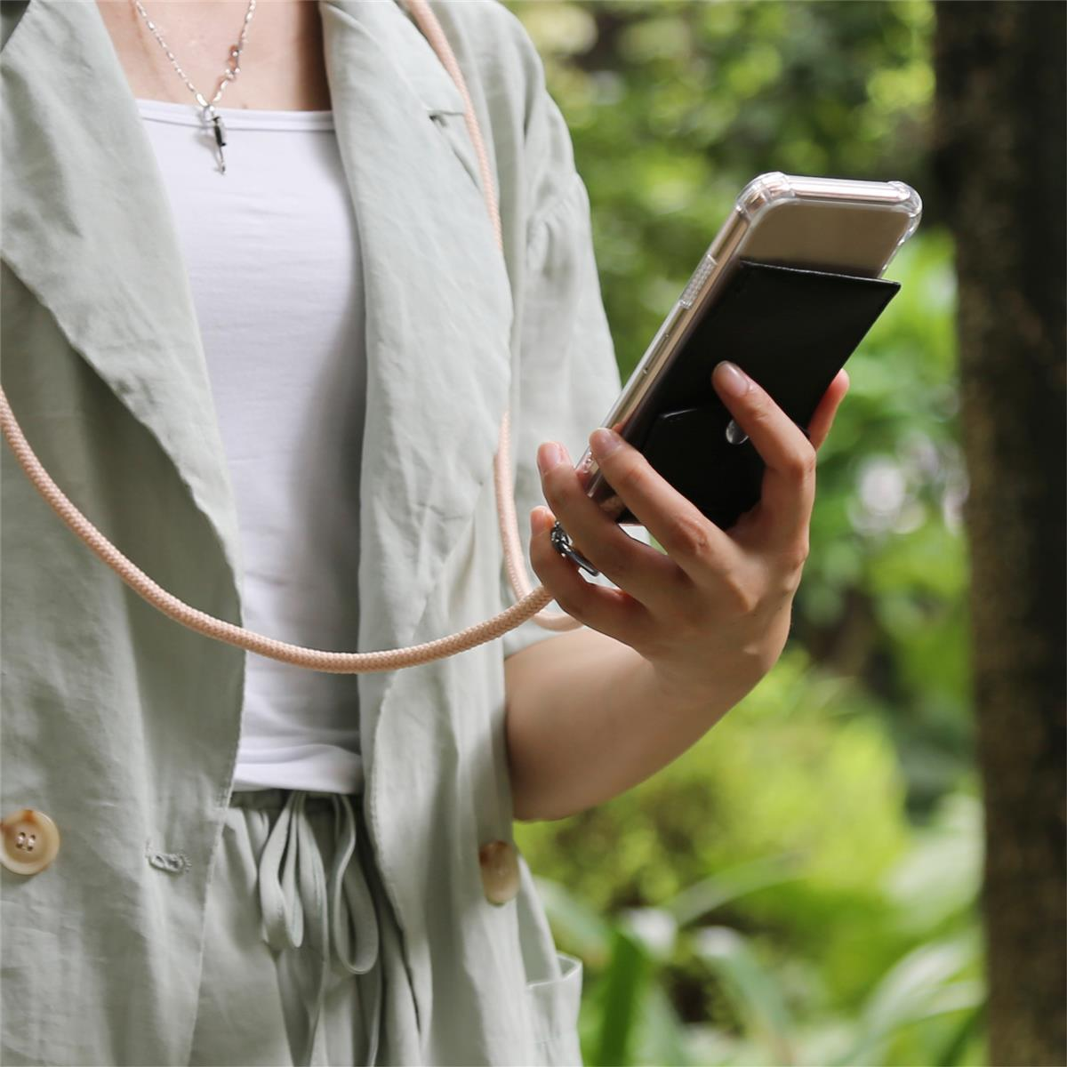 Person mit Telefon in schwarzer Hülle, trägt grüne Jacke und weißes Oberteil. Die Kordel ist rosa.