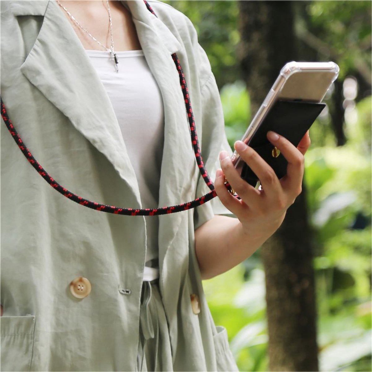 Persona che tiene un telefono con un cordino. Il telefono è in una custodia nera.