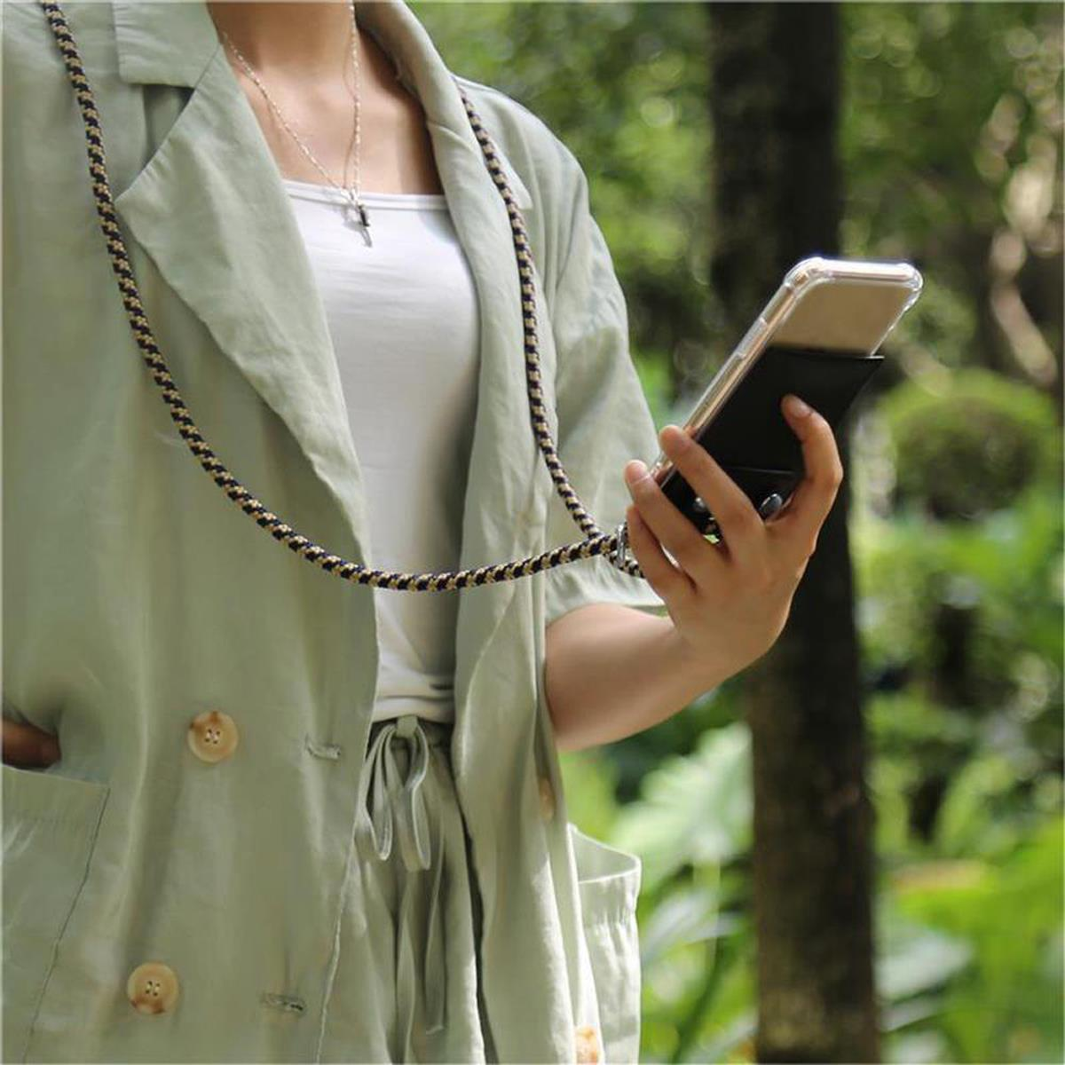 Donna che tiene in mano un telefono in una custodia nera, indossa una giacca verde e un top bianco.