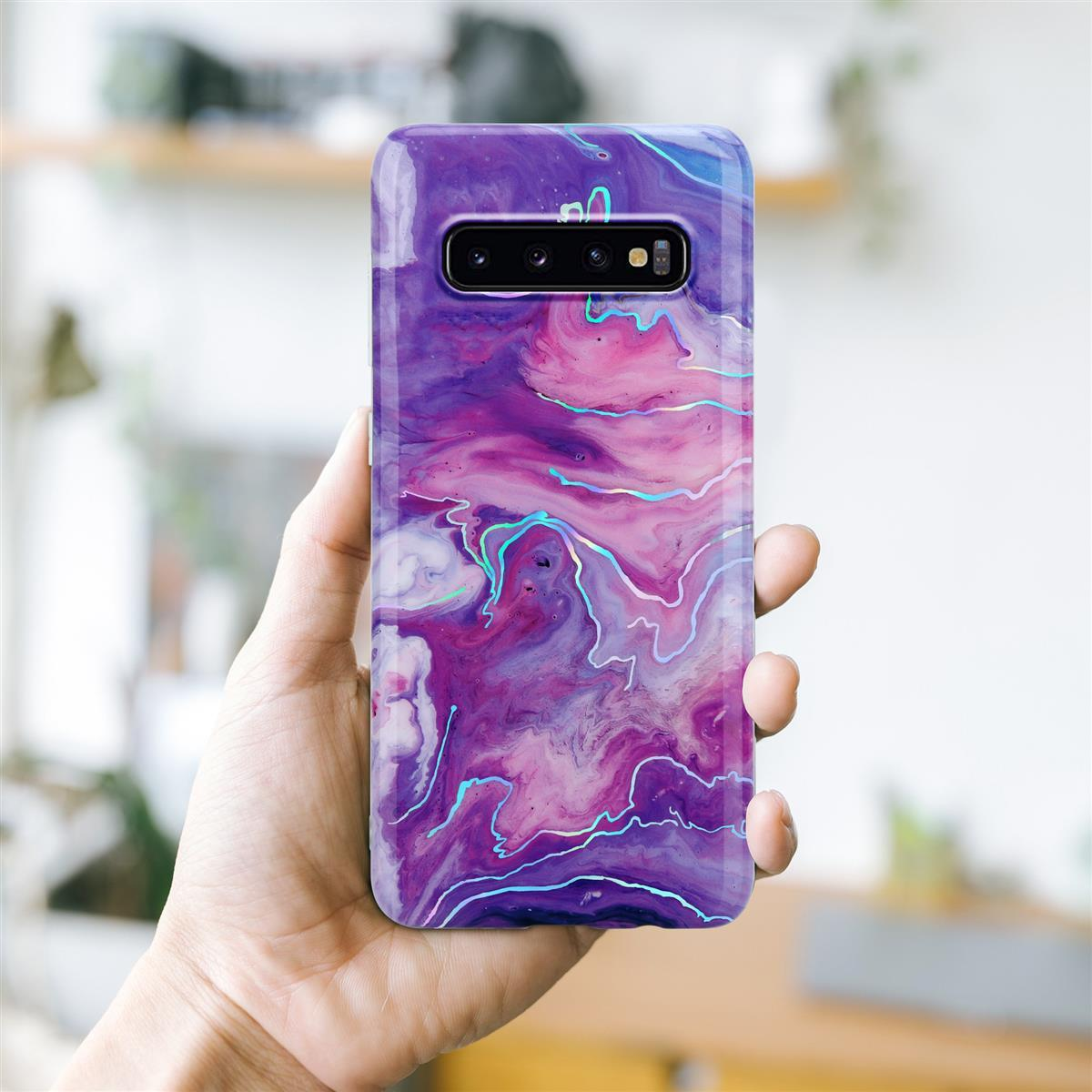 Mano che tiene un telefono con una custodia per telefono con un design marmorizzato viola, rosa e blu.