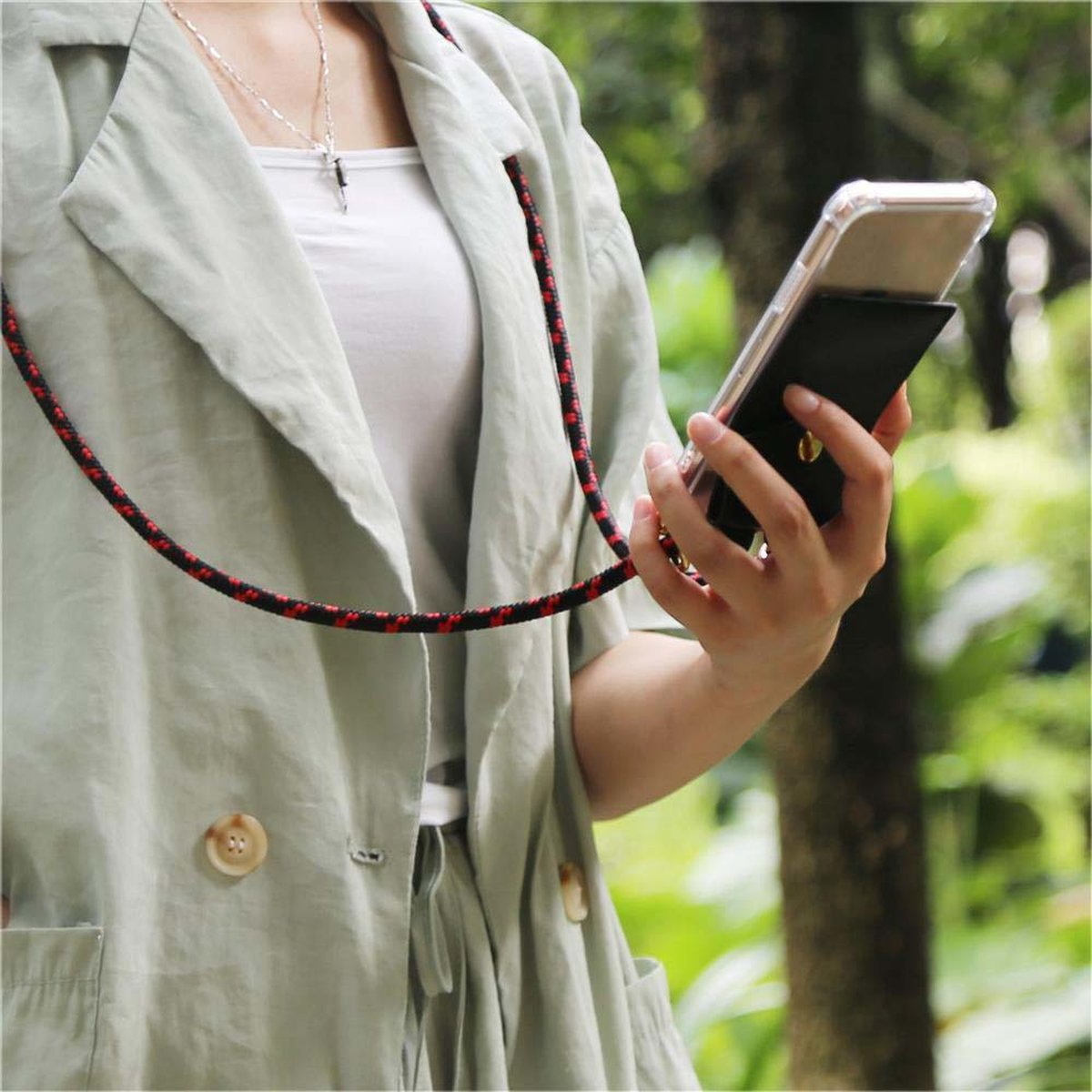Una persona tiene in mano un telefono con una custodia a portafoglio nera e un cinturino.