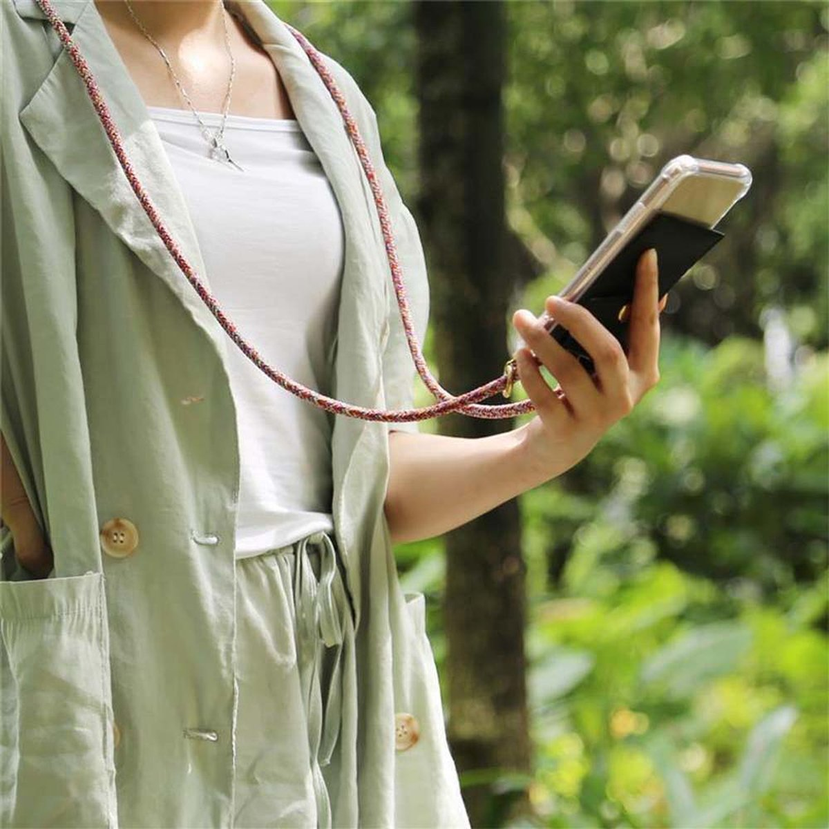 Eine Person, die ein Telefon mit Hülle und Schlüsselband hält. Die Person trägt draußen eine Jacke.