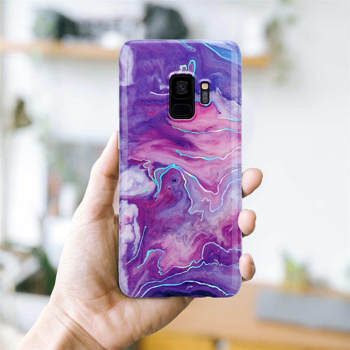 Mano che tiene una custodia per telefono con un design astratto viola e rosa.