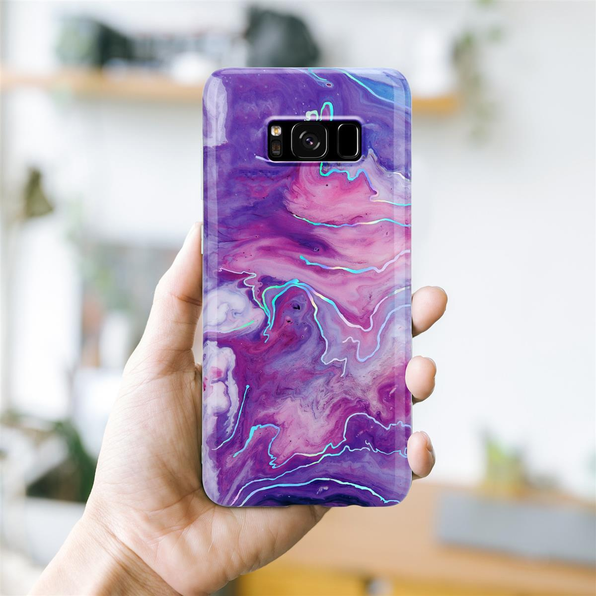 Una mano che tiene un telefono con una custodia per telefono dal design astratto viola e rosa.