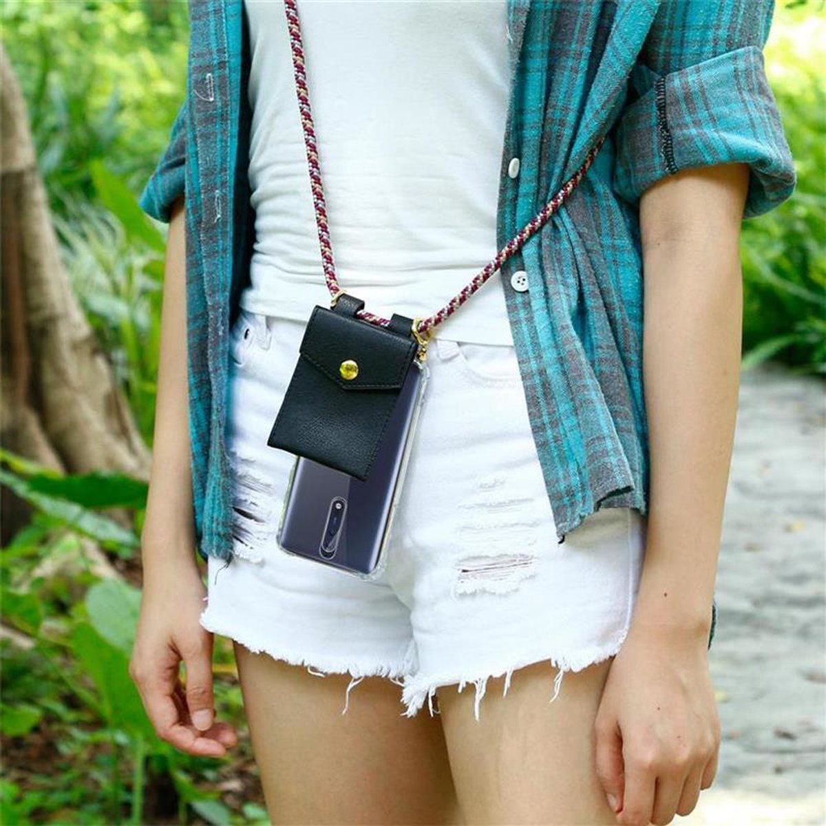 Frau mit Telefon in schwarzer Hülle an einem Band, weiße Shorts, blaues kariertes Hemd.
