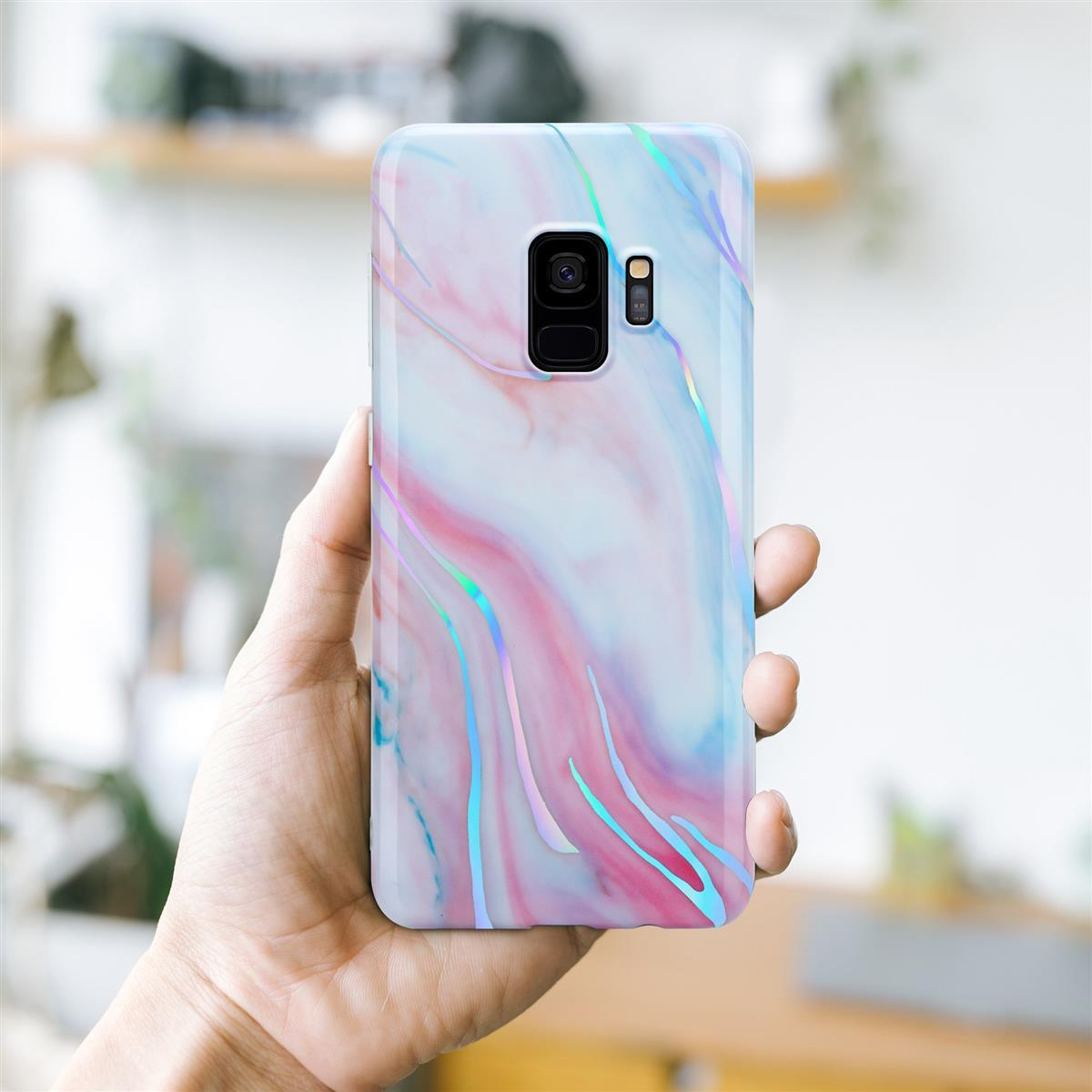 Mano che tiene una custodia per telefono con motivo marmoreo, tonalità rosa e blu, e fotocamera.