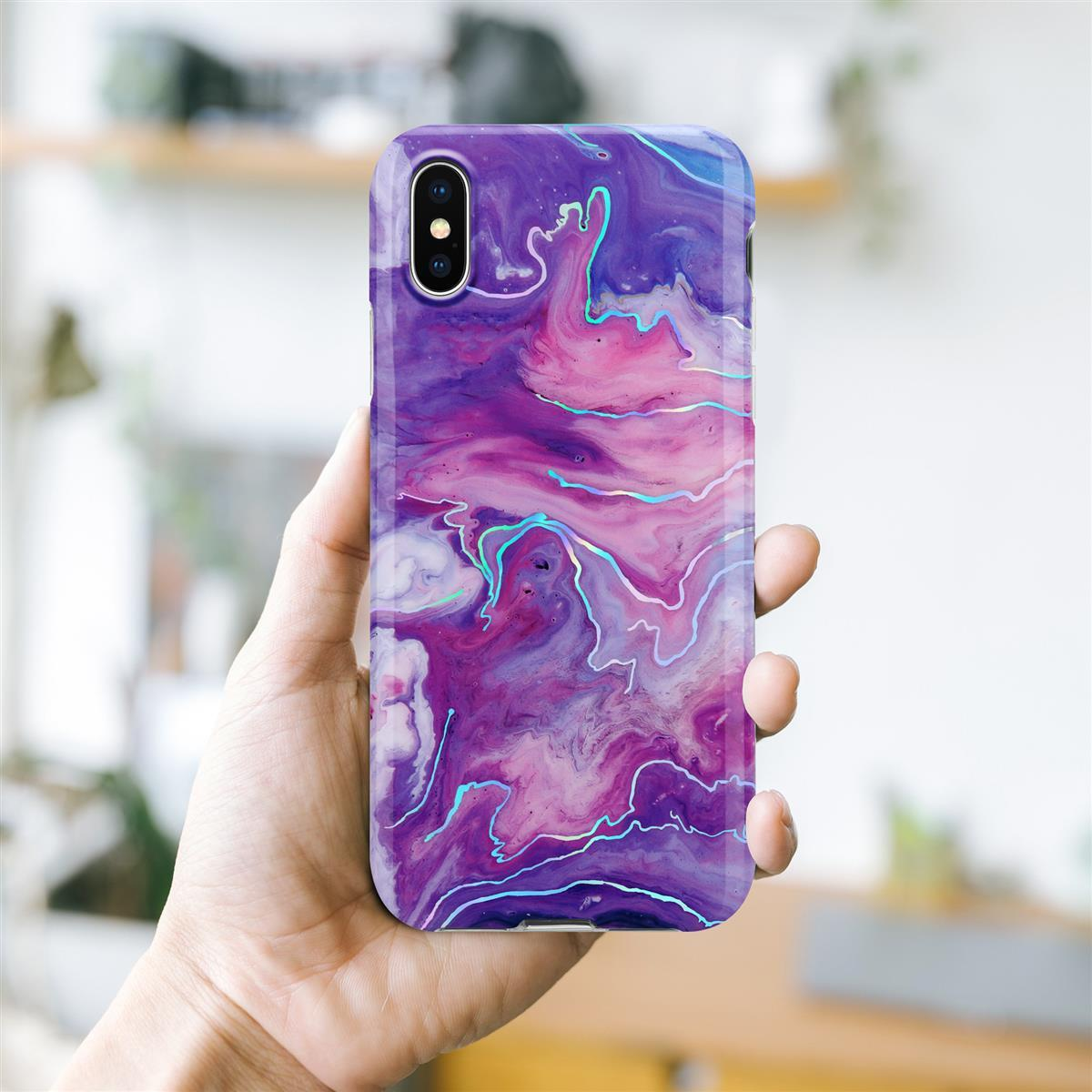 Mano che tiene un telefono con una custodia per telefono dal design a marmo viola, rosa e blu.
