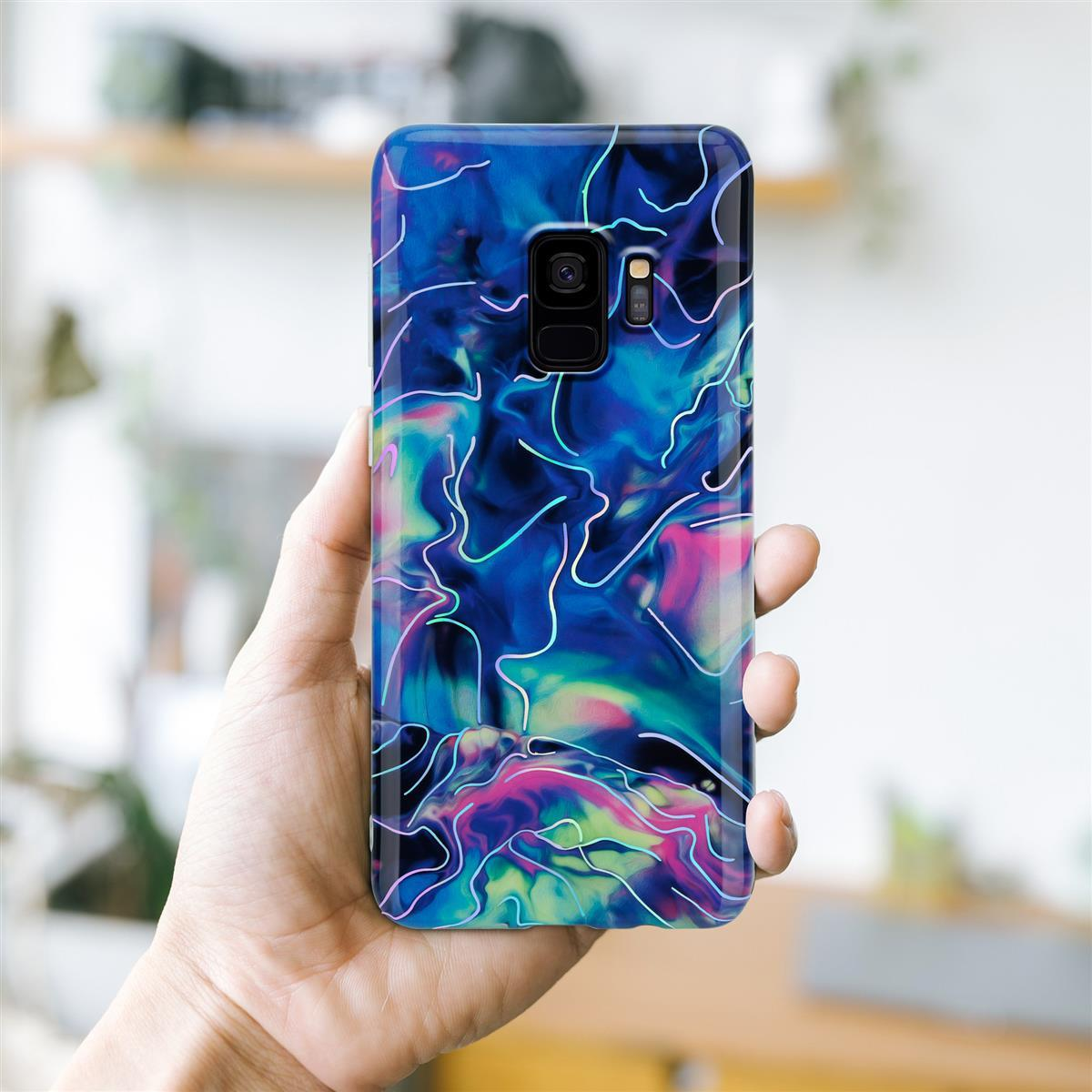 Mano che tiene una custodia per telefono con un design astratto blu e rosa, con linee bianche.