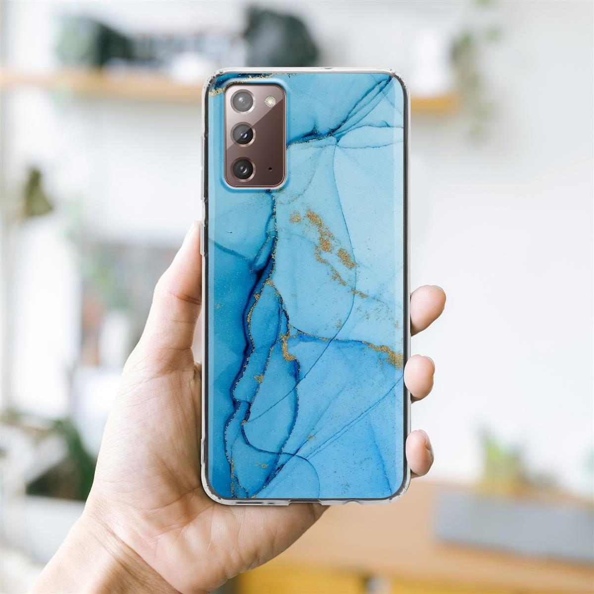 Una mano che tiene un telefono con una custodia blu marmorizzata, con venature dorate, su uno sfondo sfocato.