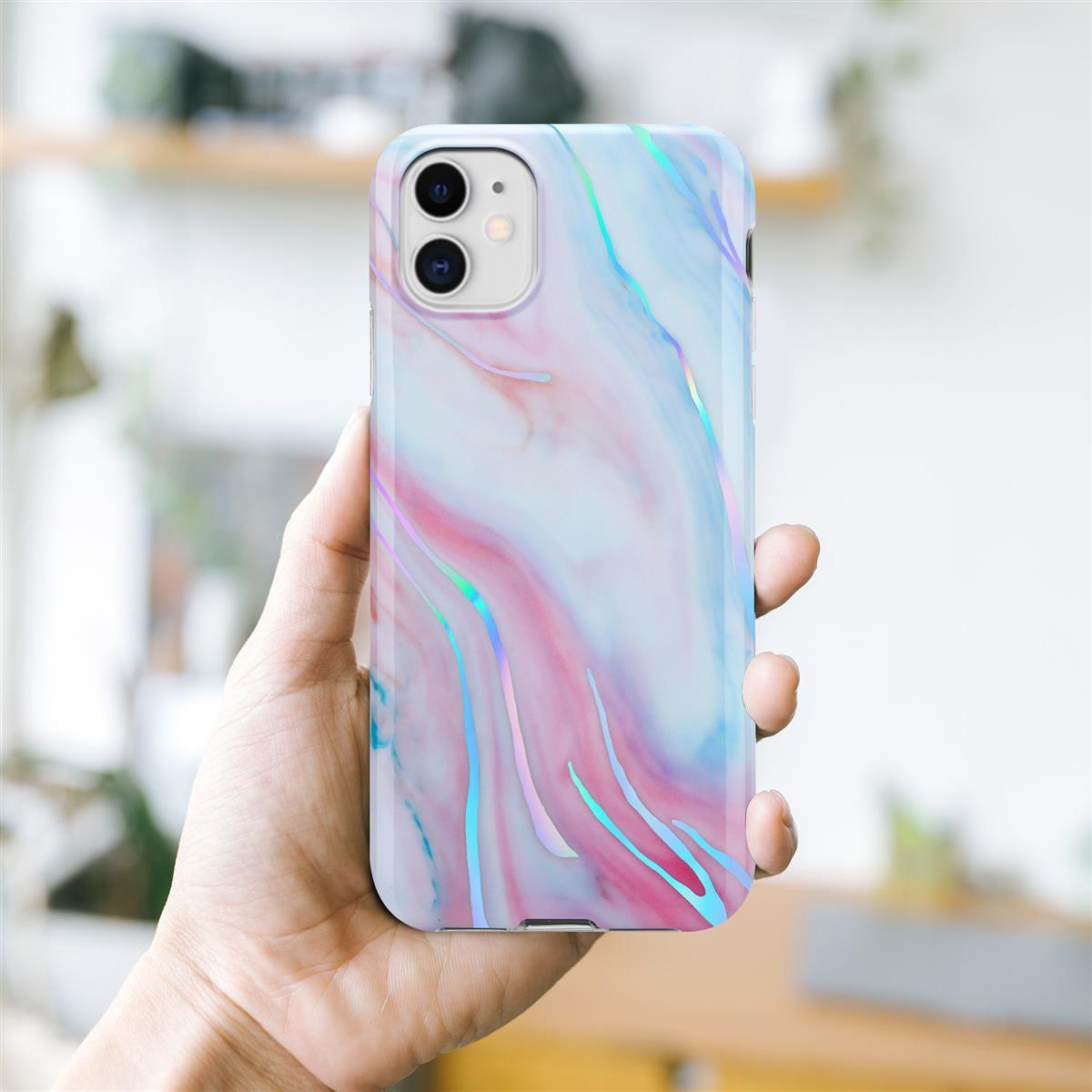 Mano che tiene un telefono con una custodia dal design marmoreo colorato. Sfondo: mensola sfocata.