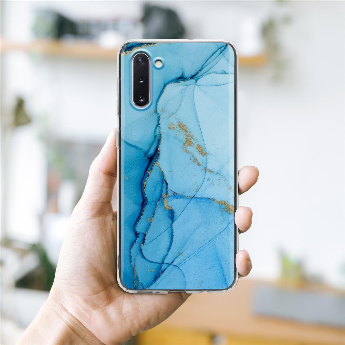 Una custodia per telefono con un motivo marmorizzato blu e oro. È tenuta in mano.
