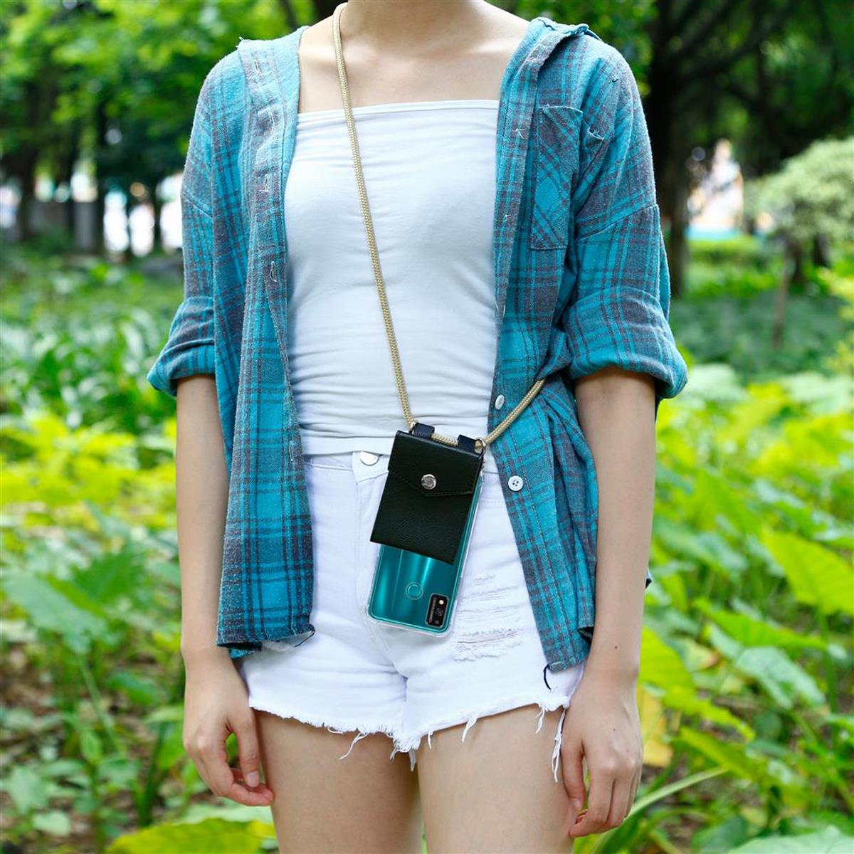 Donna con custodia per telefono e cordino in un parco. Indossa una camicia a quadri e pantaloncini.