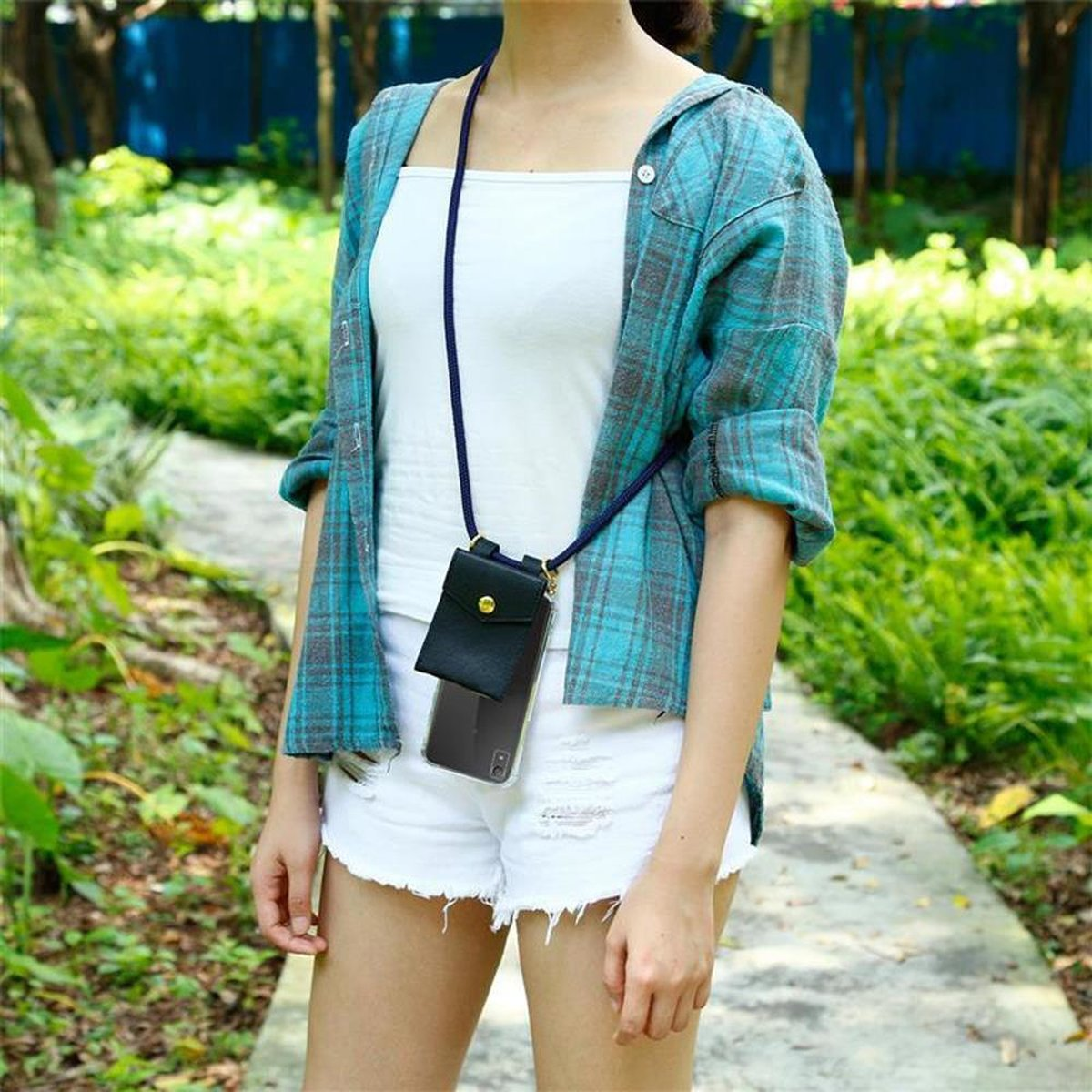 Frau mit blauem Hemd und weißen Shorts, die ein Telefon mit einem Lanyard trägt.
