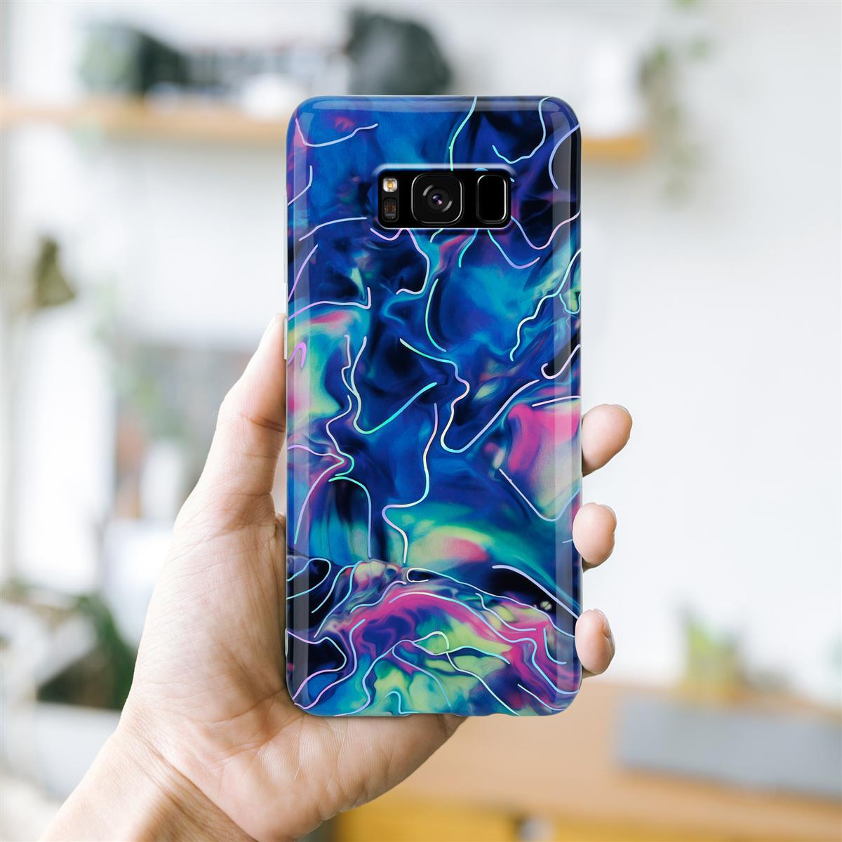 Mano che tiene una custodia per telefono con un design astratto colorato su sfondo sfocato.