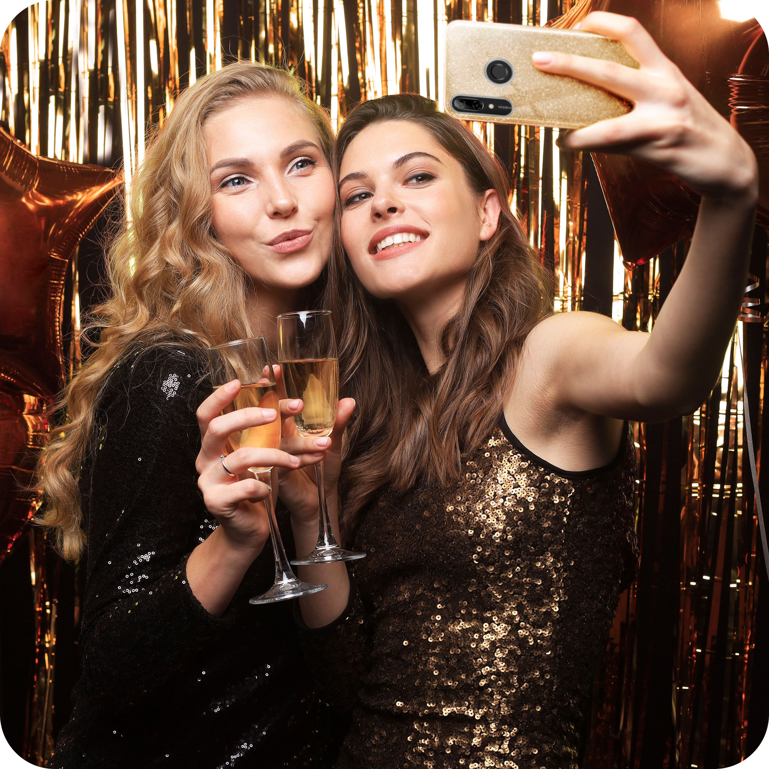 Zwei Frauen machen ein Selfie mit Champagnergläsern vor goldenem Hintergrund.