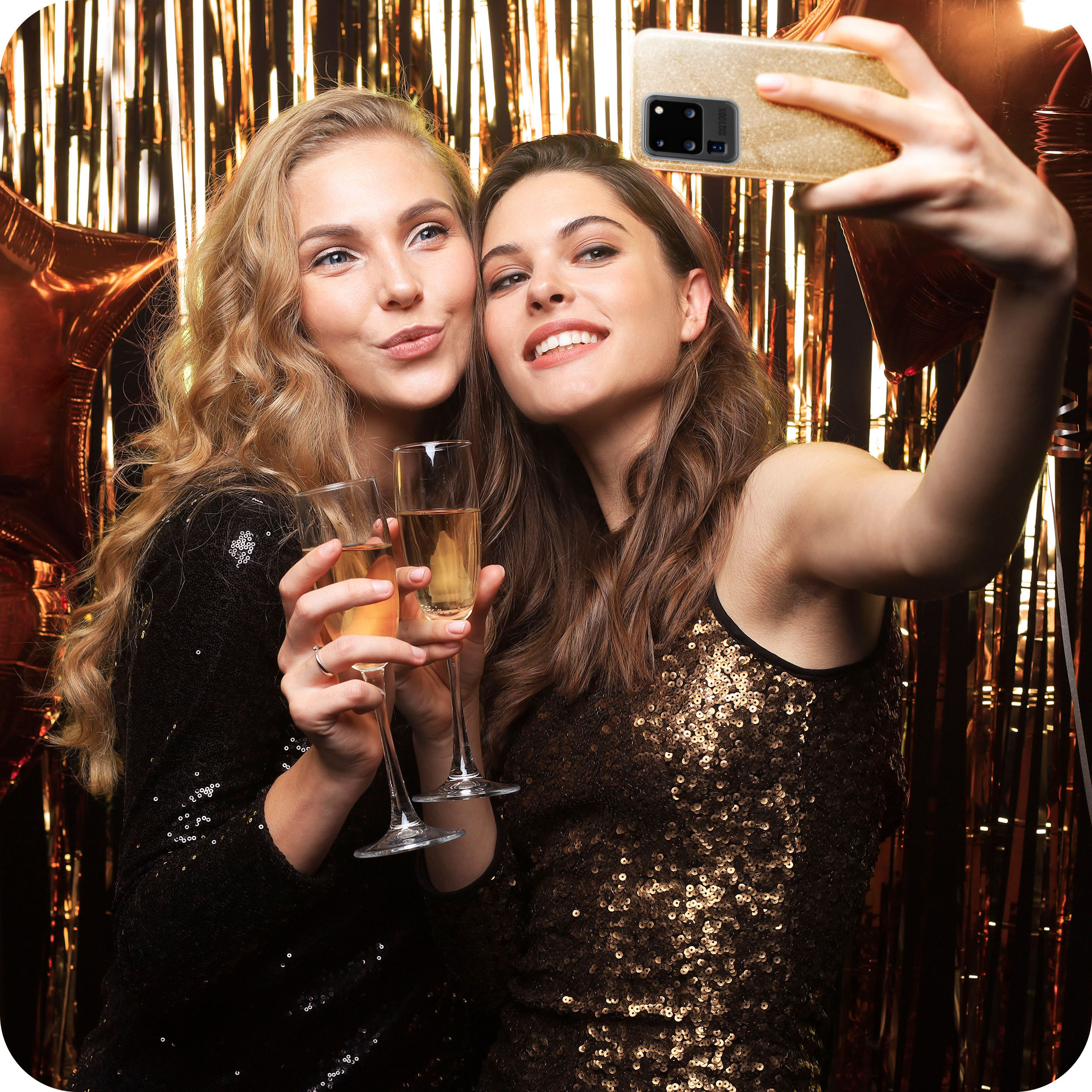 Zwei Frauen machen ein Selfie mit einem goldenen Telefon, beide lächeln.