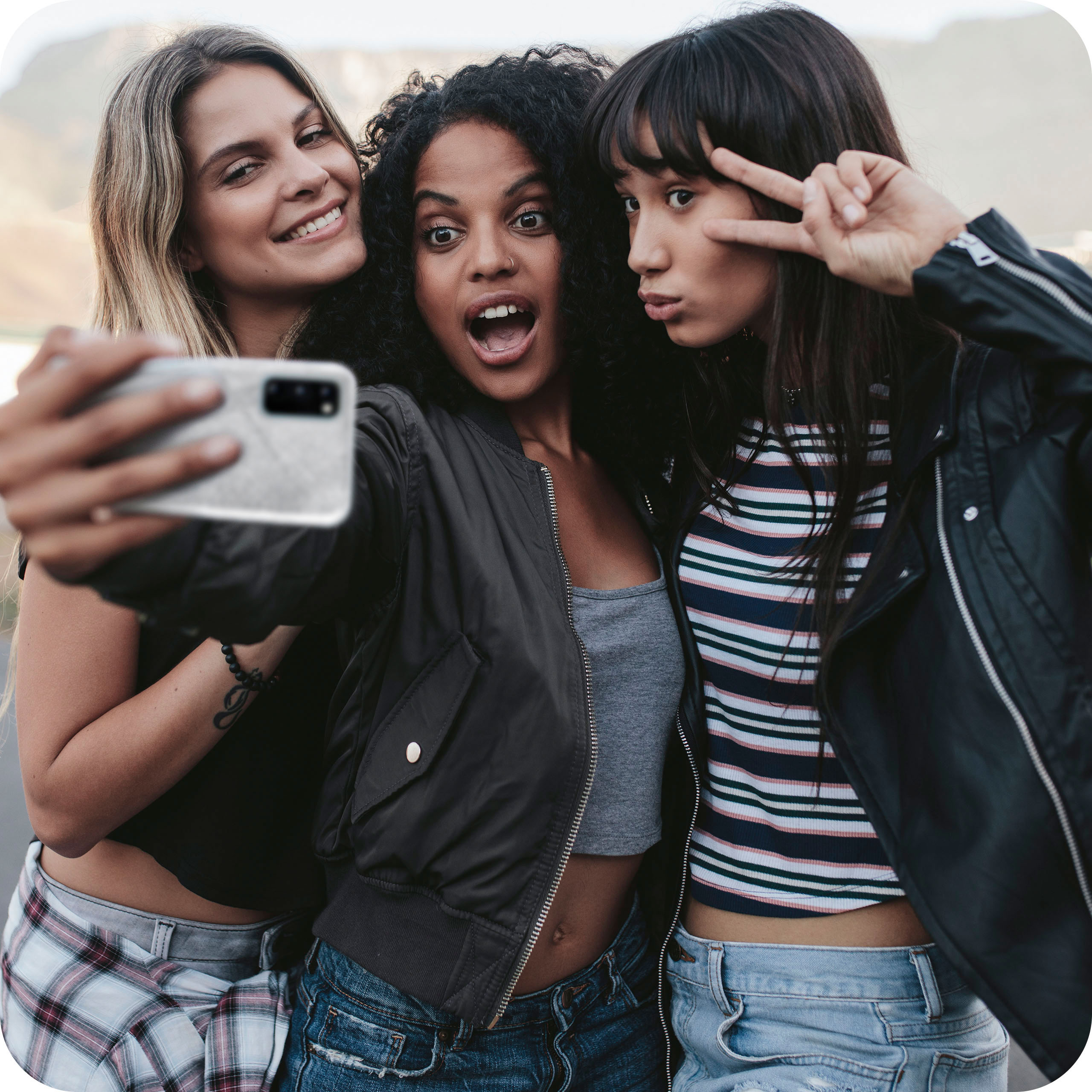 Drei Frauen machen ein Selfie, eine macht ein Friedenszeichen, eine überrascht.