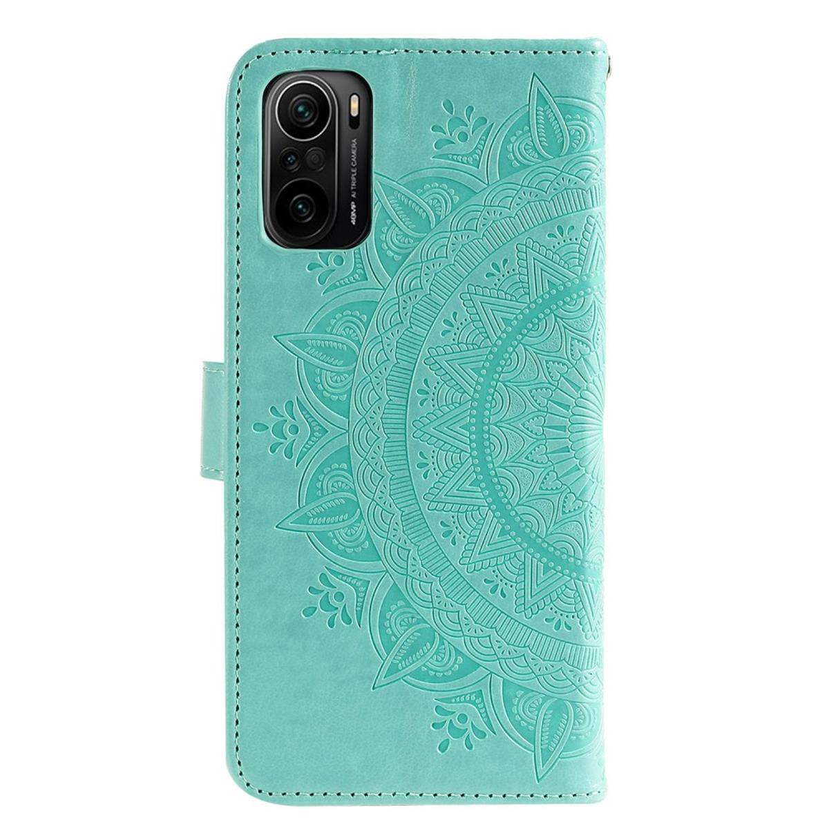 Eine türkisfarbene Handyhülle mit Mandala-Design, geöffnet, um das Telefon und seinen Kamerabereich zu zeigen.