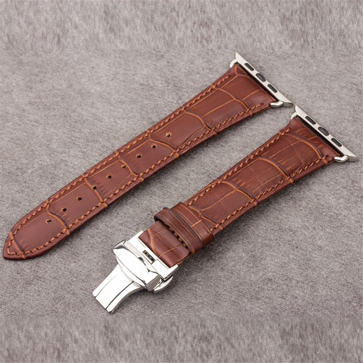 Braunes Krokodilleder-Uhrenarmband mit silberner Schnalle und Anschlüssen, auf grauer Oberfläche.