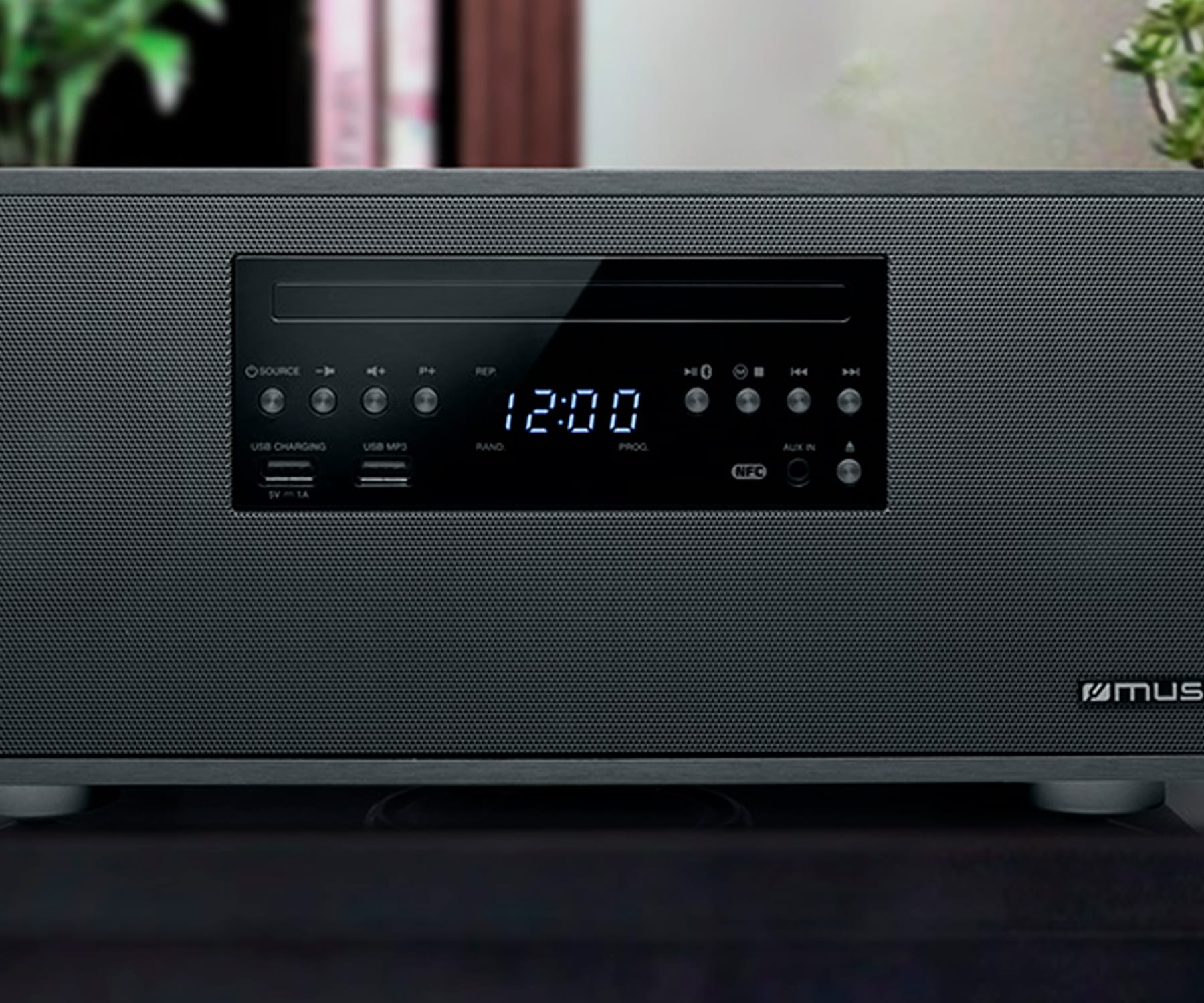 Un sistema de música digital negro muestra las 12:00 en su pantalla. Tiene botones para varias funciones.