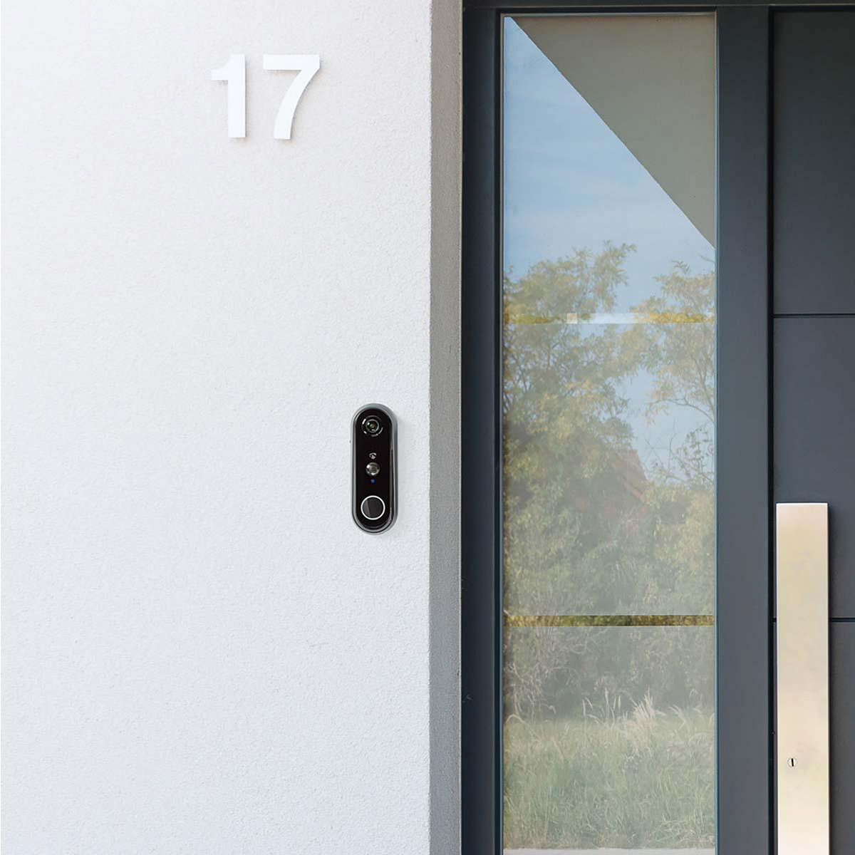 Un mur blanc avec une sonnette et le numéro 17. Une porte vitrée est à droite.