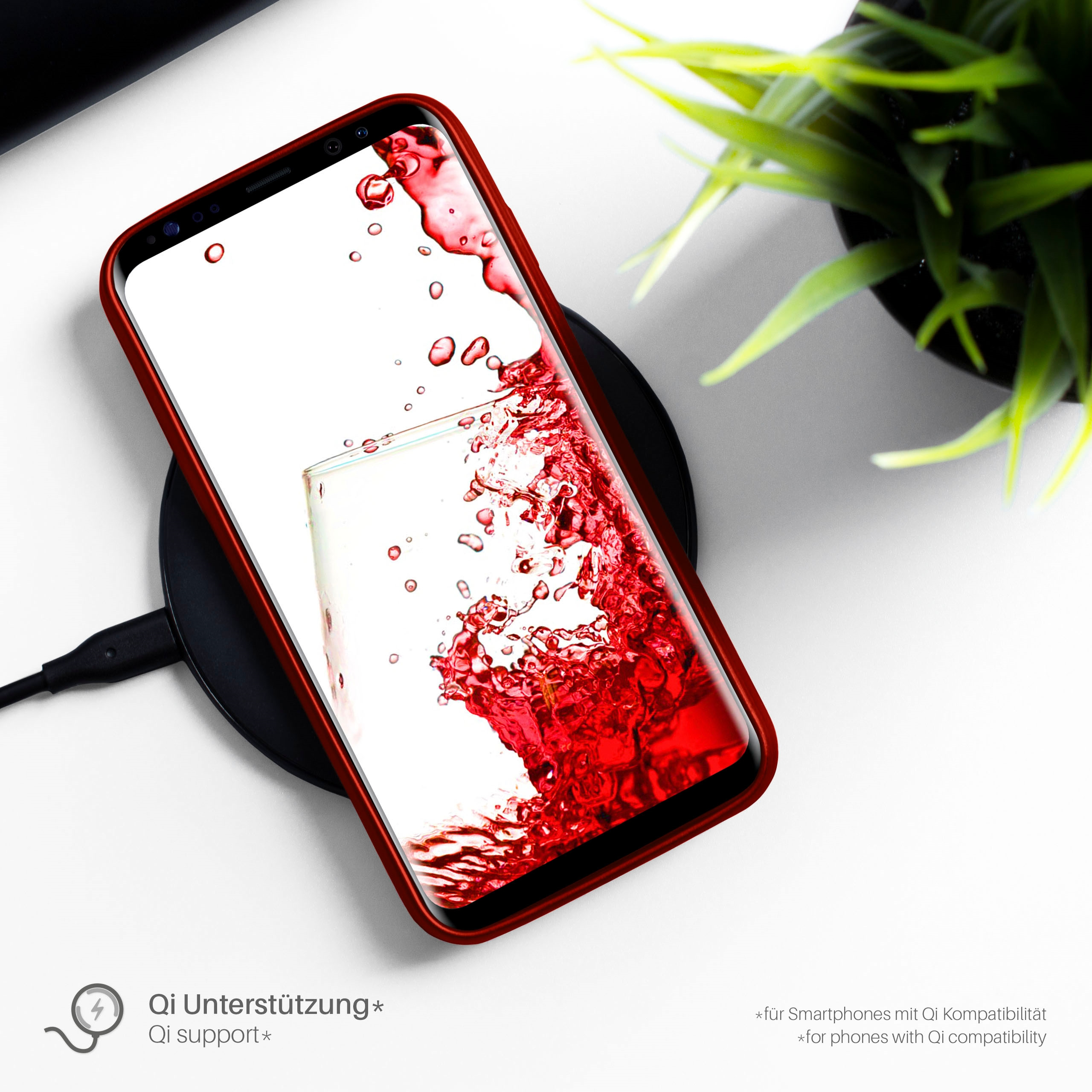 Smartphone auf kabellosem Ladegerät. Das Telefon hat eine rote Hülle und rote Flüssigkeit auf dem Bildschirm.