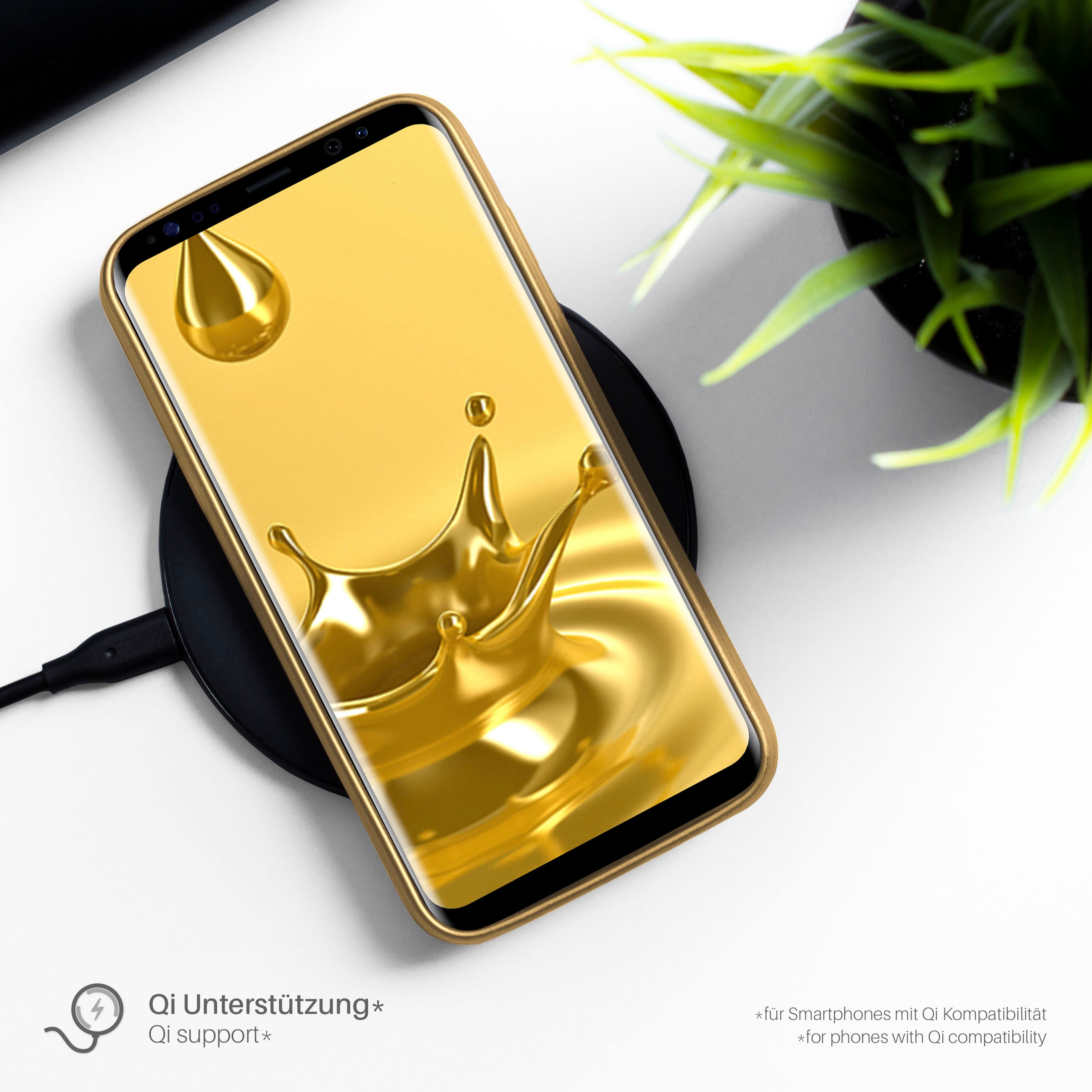 Telefon auf einem kabellosen Ladegerät. Das Telefon hat ein goldenes Gehäuse. Im Hintergrund ist eine Pflanze zu sehen.