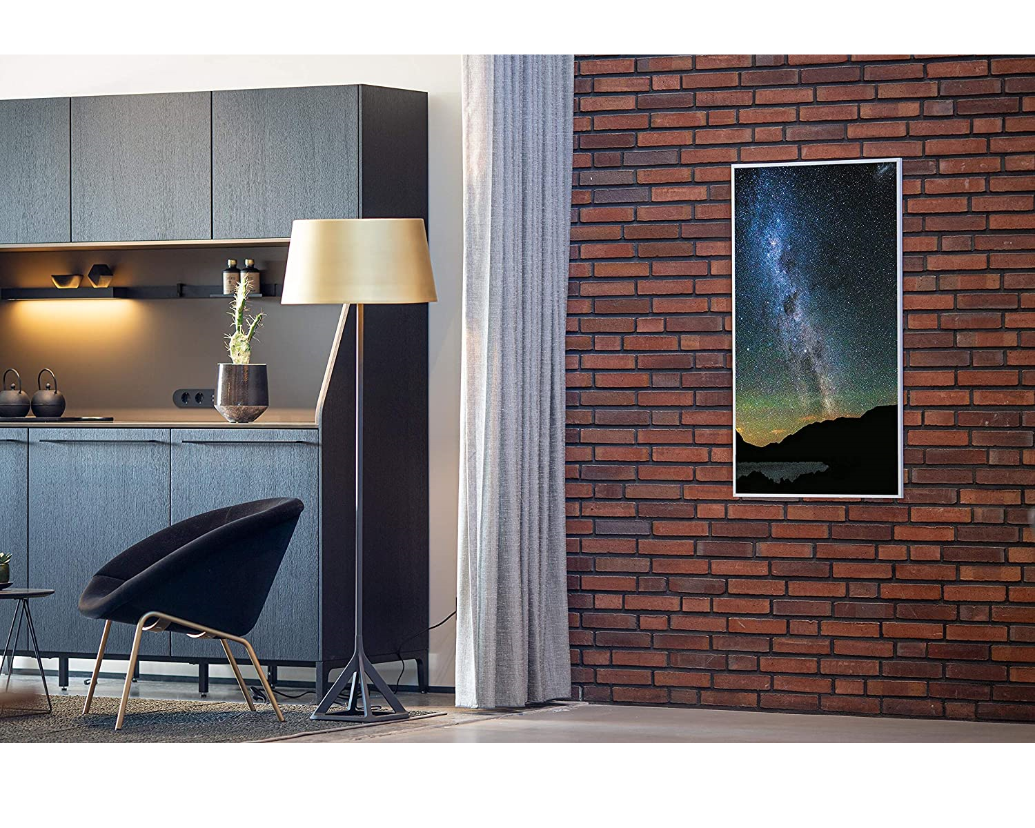 Innenraum mit Backsteinmauer, schwarzem Stuhl, Stehleuchte und Galaxienbild.