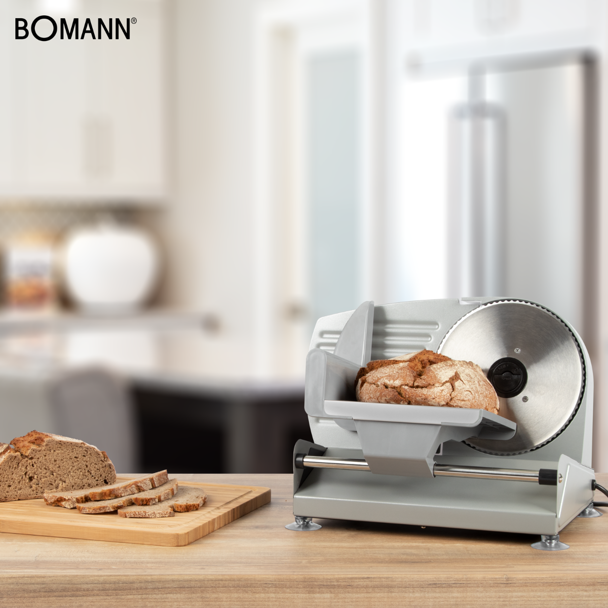 Krajalnica do chleba na drewnianym stole. Obecne są również kromki chleba i bochenek. Marka BOMANN.