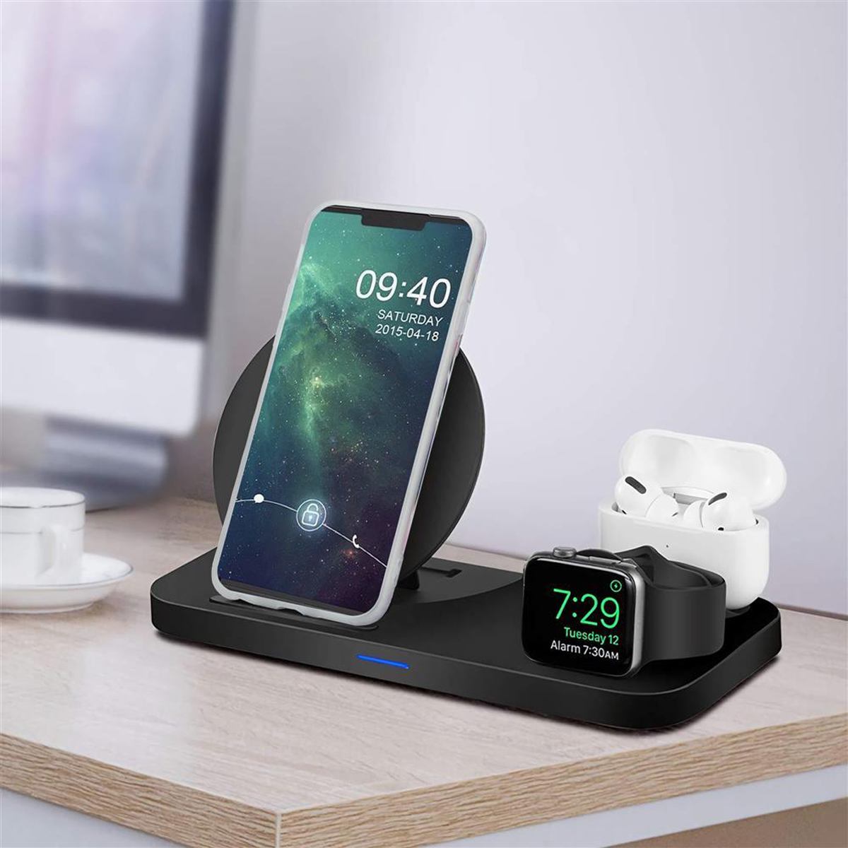 Stazione di ricarica wireless con telefono, smartwatch e auricolari su una scrivania.