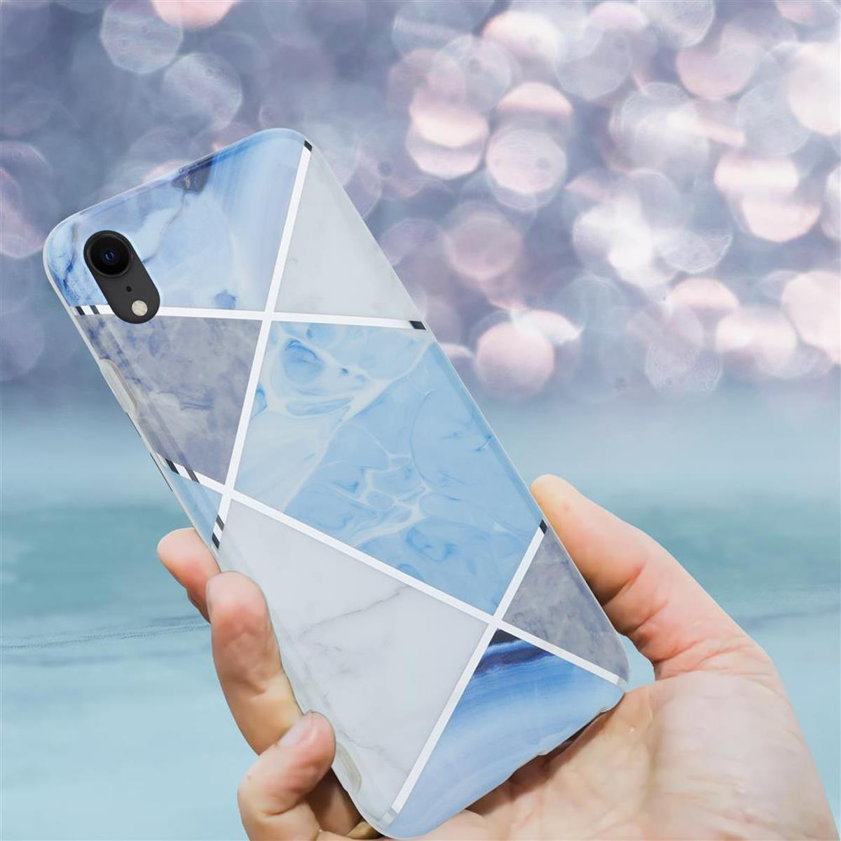 Mano che tiene una custodia per telefono fantasia. La custodia ha un design marmorizzato bianco, blu e grigio.