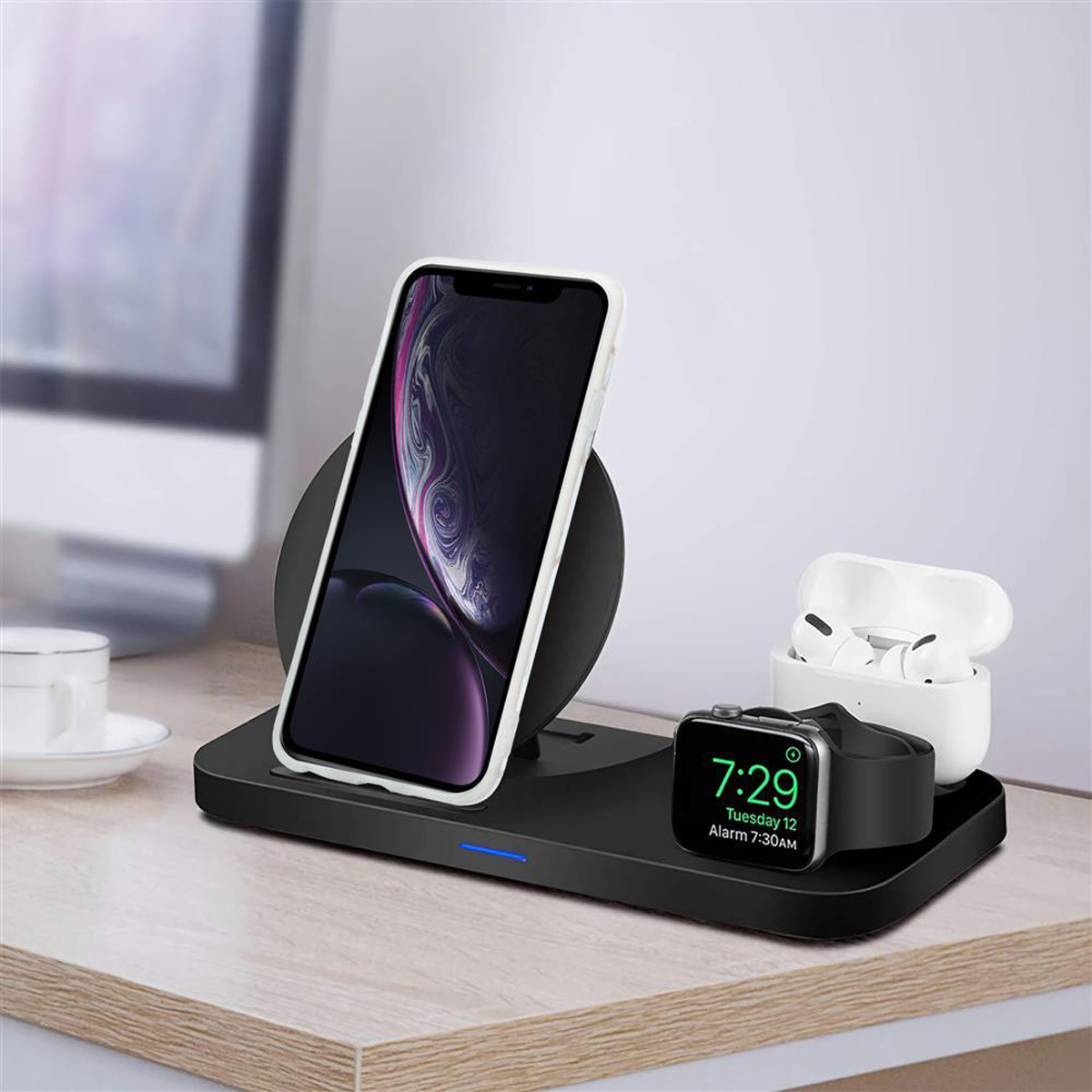 Stazione di ricarica con telefono, AirPods e smartwatch su una superficie in legno.