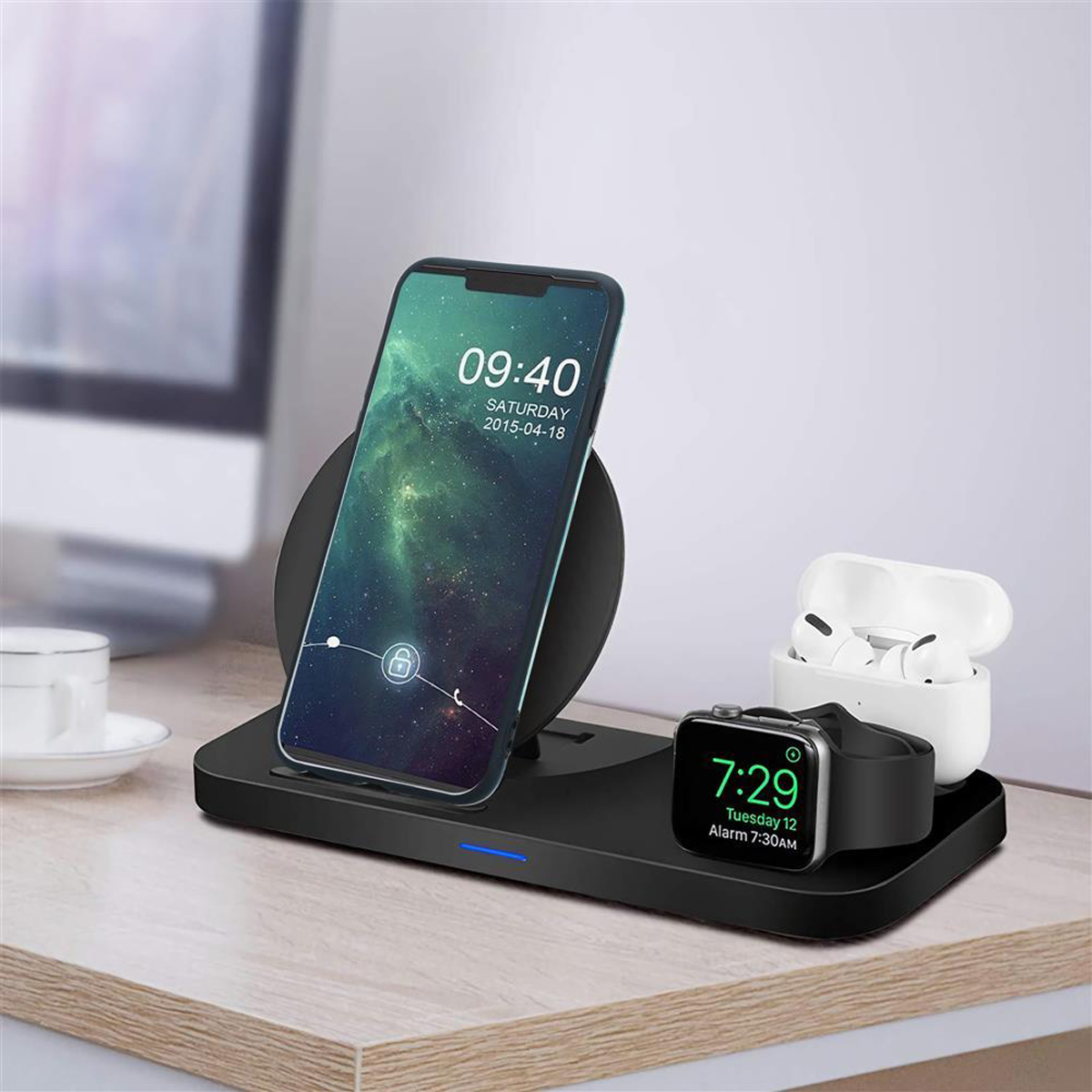 Stazione di ricarica wireless con un telefono, Apple Watch e AirPods. Il telefono mostra l'ora.