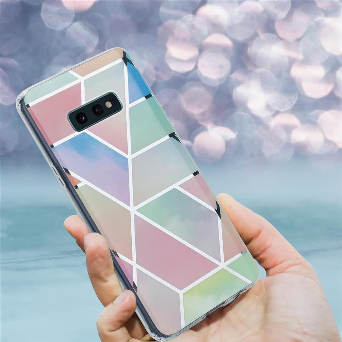 Una mano che tiene un telefono con una custodia a motivi geometrici colorati. Lo sfondo è sfocato.