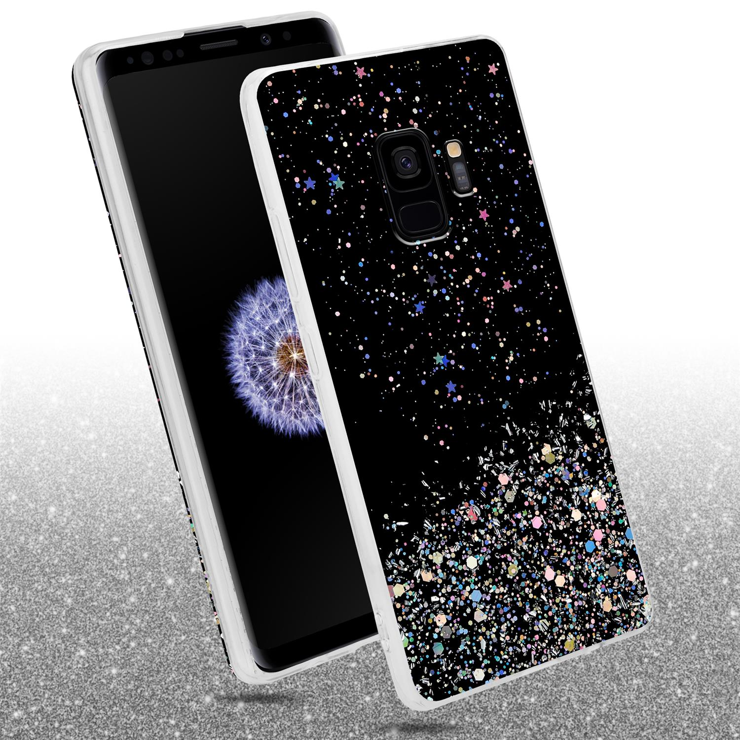 Telefon mit schwarzer Hülle mit Glitzer. Das Telefon befindet sich auf einer Glitzeroberfläche.