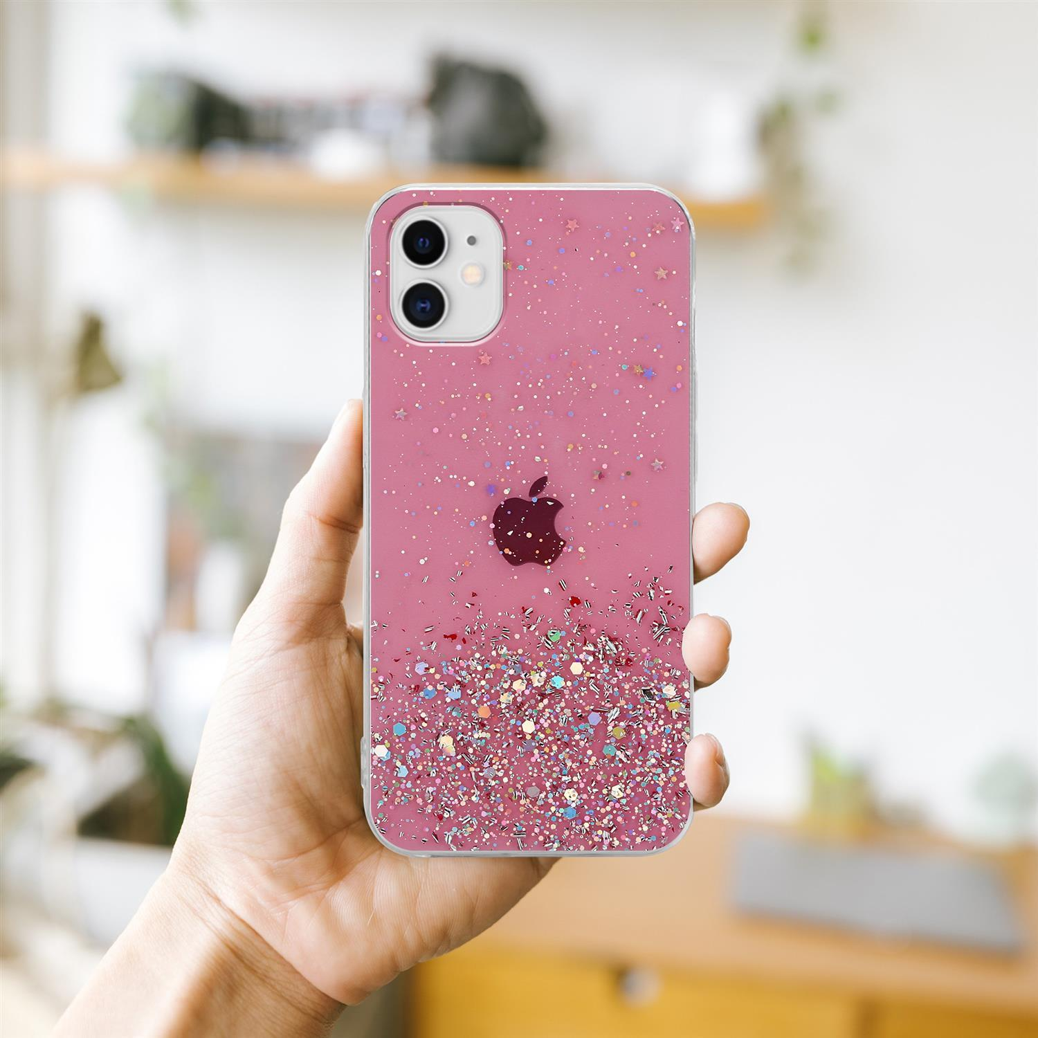 Hand hält eine rosa Handyhülle mit Glitzer. Die Hülle hat ein dunkles Apple-Logo. Verschwommener Hintergrund.