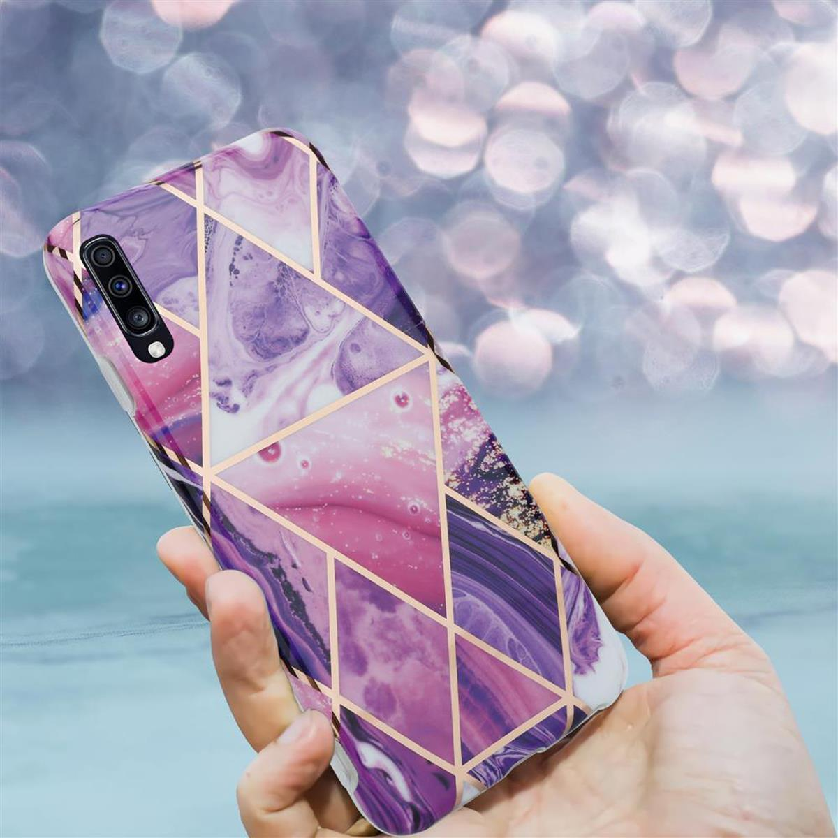 Una mano che tiene una custodia per telefono con un design geometrico viola e oro.